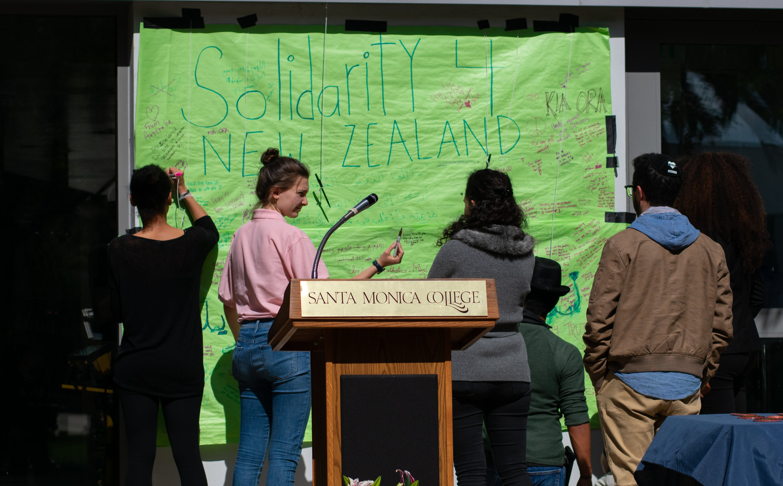  Students write messages to those in New Zealand  on a poster just before a vigil for the victims of the Christchurch shootings on Wednesday March 20th 2019 at Santa Monica College (SMC), Santa Monica Calif. (Photo by Conner Savage Corsair Staff) 