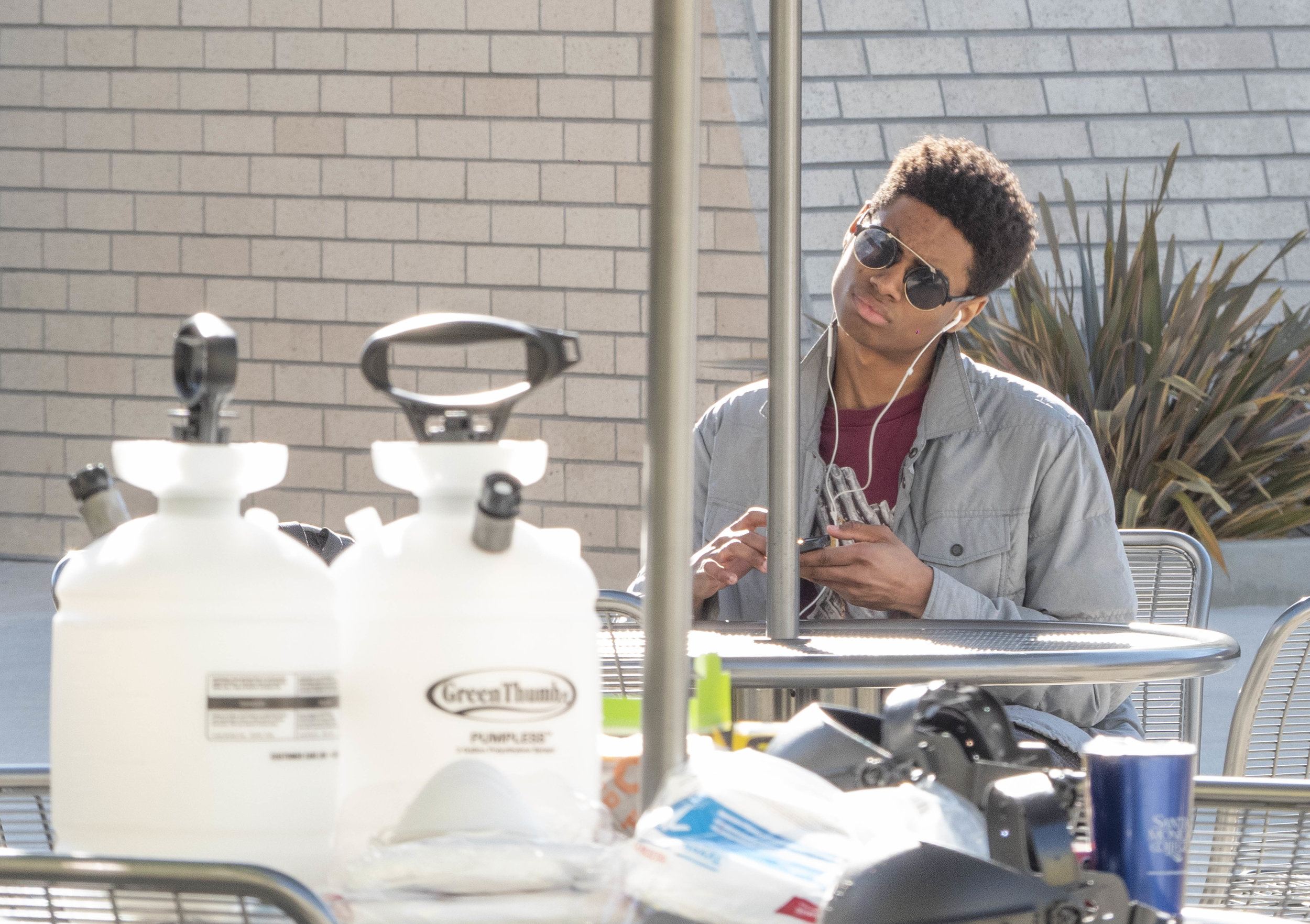 Andrel White, a film major, sits at an umbrella table, while another umbrella table in front of him is adorned with cleaning supplies. A chemical smell caused a building closure at the Center for Media Design. The building and computer lab will open again at 1pm according to facility staff. Friday, April 5, 2019, Santa Monica College, Santa Monica, California. (Victor Noerdlinger/Corsair)