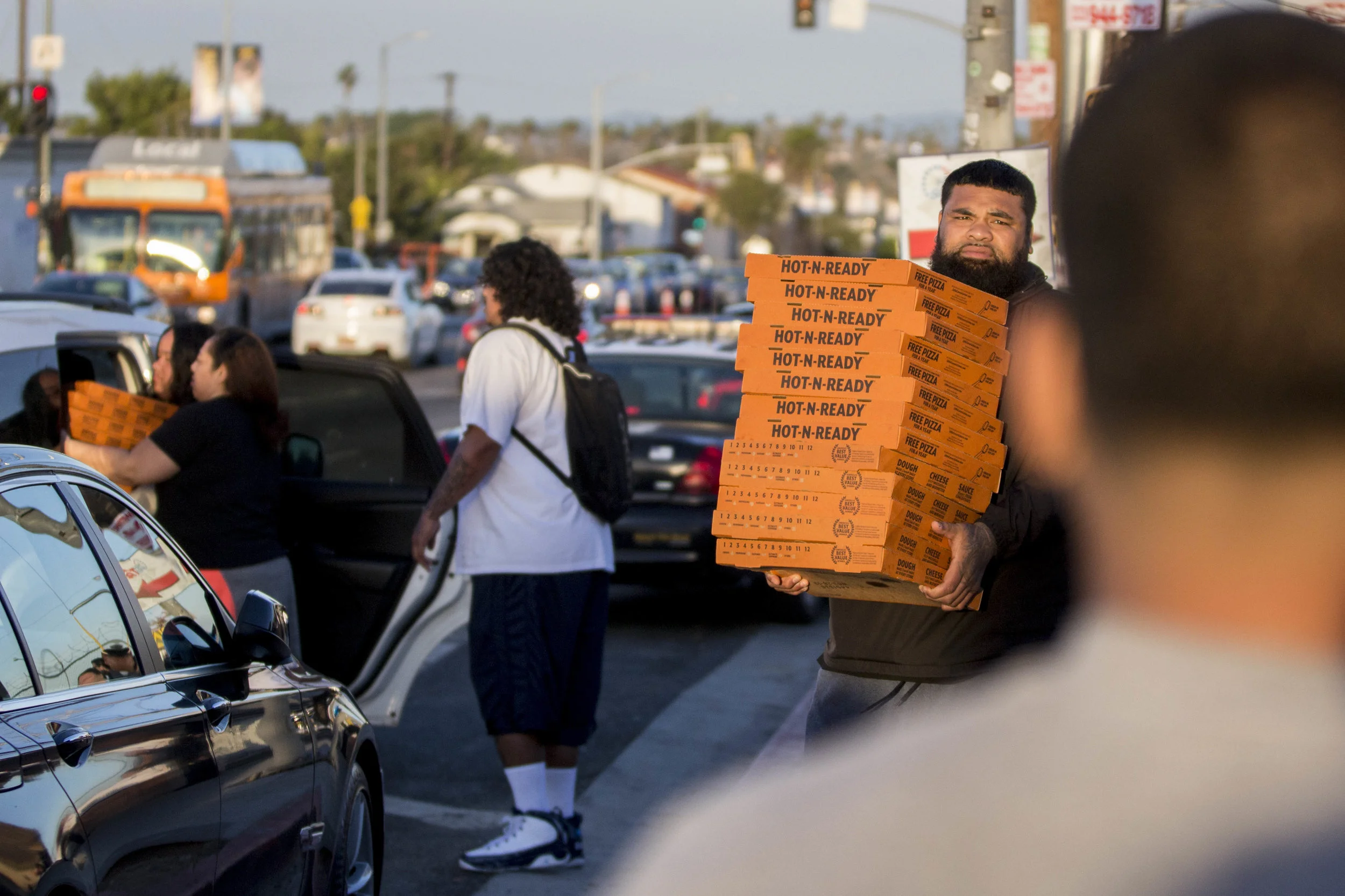 A man helps unload a car and carries a stack of pizzas over to the area where a makeshift memorial honoring Nipsey Hussle is set up so they can feed all the family and fans who have come out to pay their respects to the slain rapper at The Marathon Clothing store in Los Angeles, California on April 6, 2010. Renei Ngaue Fangupo along with her cousin and family wanted to do something to give back to the community, in the name of Nipsey Hussle who was known to be generous and very giving to the Tongan community. As a result they came out to the makeshift memorial on Tuesday, April 2 to set up a taco stand to feed people to keep their stomachs full and put their spirits at ease. It was from there that the idea grew and Vikashari Moala along with her family wanted to continue the give away by putting out the word that they would be back on Saturday. Over a 100 people participated in the giveaway which included around 300 pizzas, some sandwiches, chips, and sodas. Fangupo said, “We basically wanted people to feel free to come out and eat, in the same way that Nip welcomed everybody here at The Marathon Clothing store.” The 33-year-old rapper was murdered on March 31 in front of The Marathon Clothing store which he owned. (Jose Lopez)