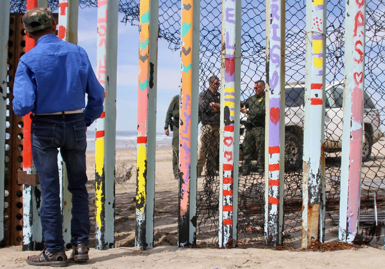 A man looks through the border wall at Border Patrol agents on standby while construction along the border wall in Playas de Tijuana took place on Friday, March 15, 2019 in Tijuana, Mexico. The construction on this section of the border wall comes after two different incidents of significantly large groups of migrants crossing through the border wall between gaps and openings on Thursday, March 14 and on Friday, March 15. (Ryan Mena/The Corsair)