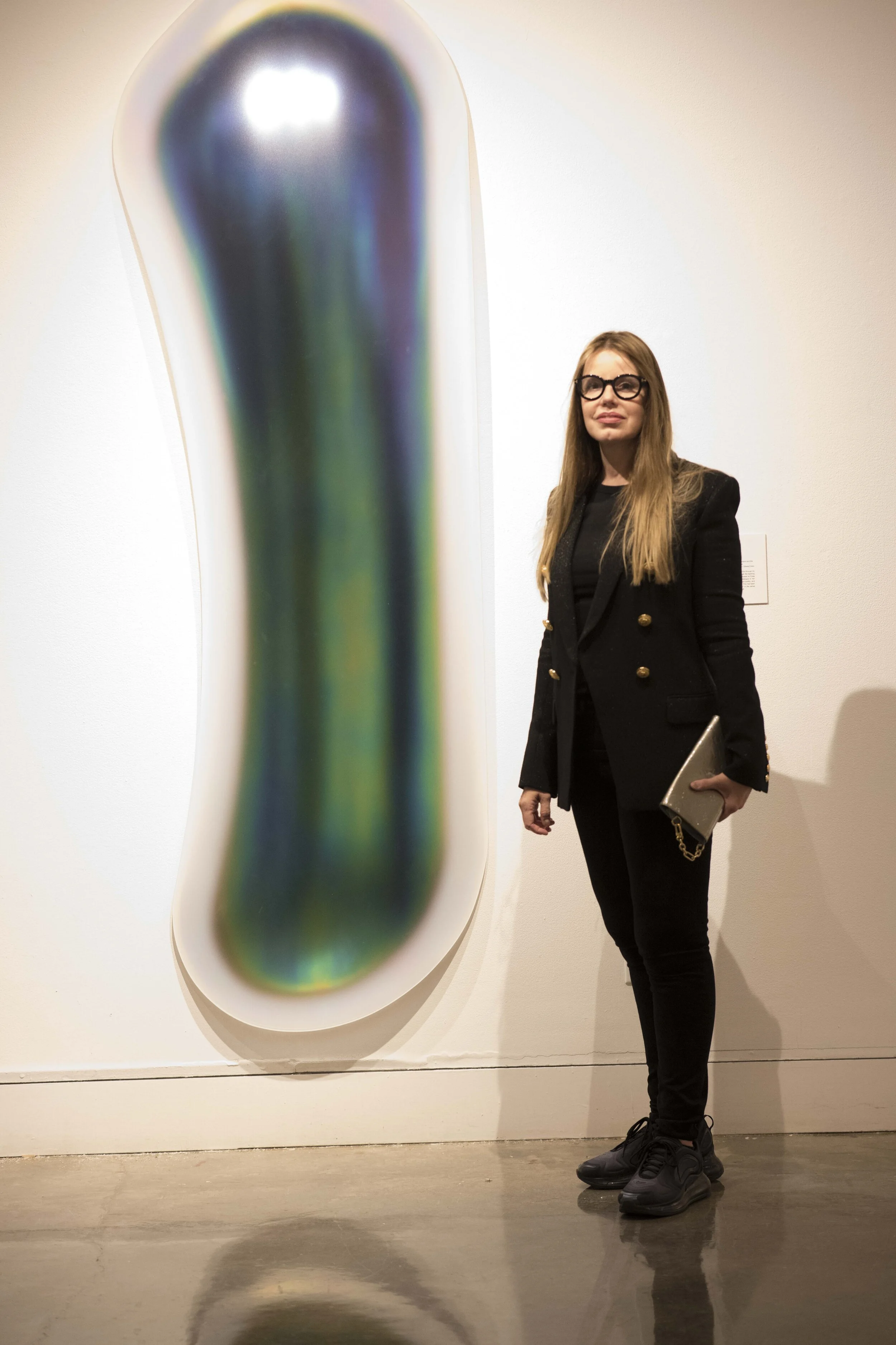 Gisela Colon poses next to her 2014 work, “Oval Melt Glo-Pod,” created from blow-molded acrylic. (Kevin Tidmore/The Corsair)