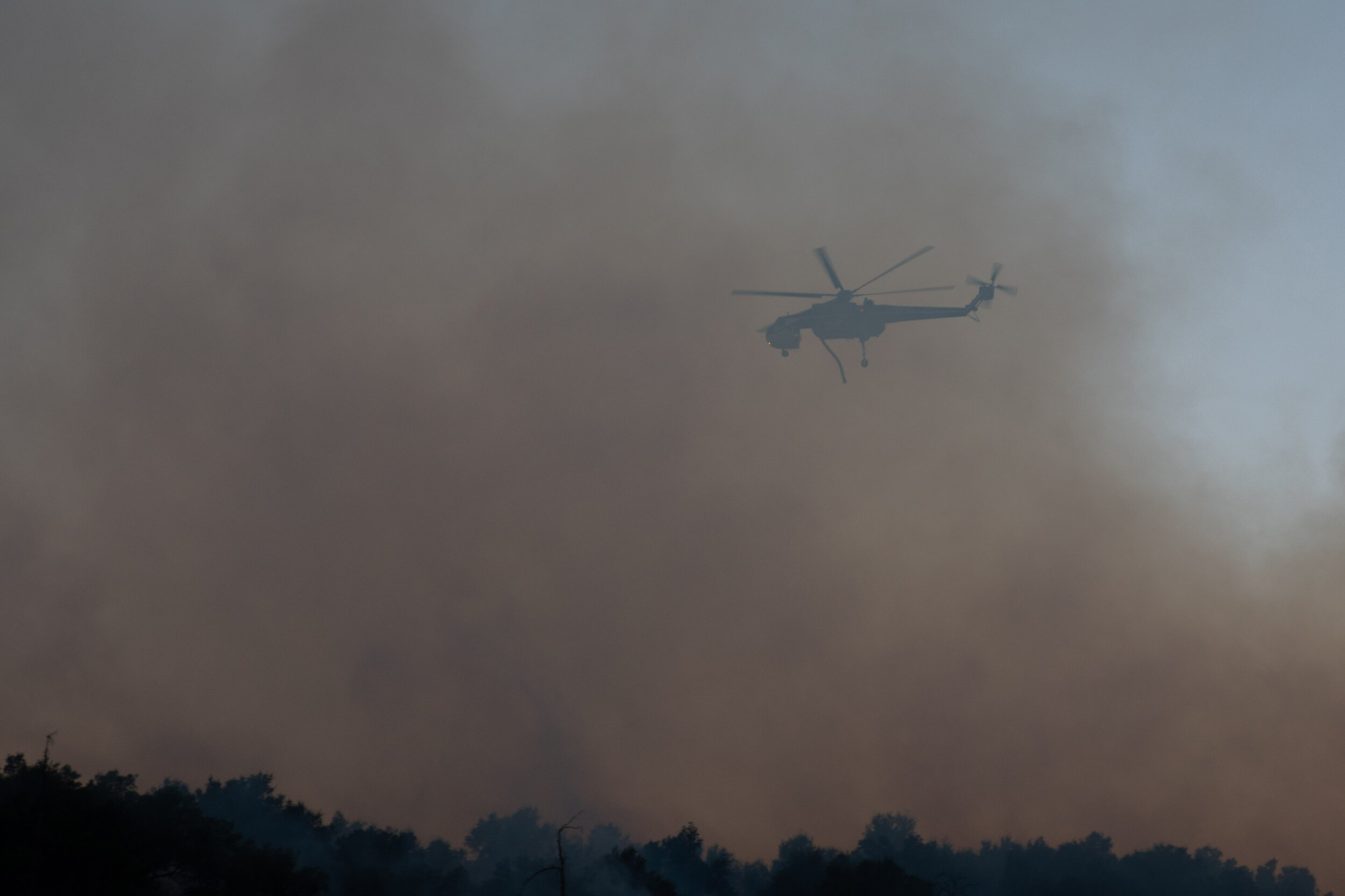 A helitanker behind a cloud of smoke just before it drops water on the Saddlerige Fire just off interstate 5 near Newhall Calif. on Friday, Oct. 11, 2019. (Conner Savage/The Corsair)
