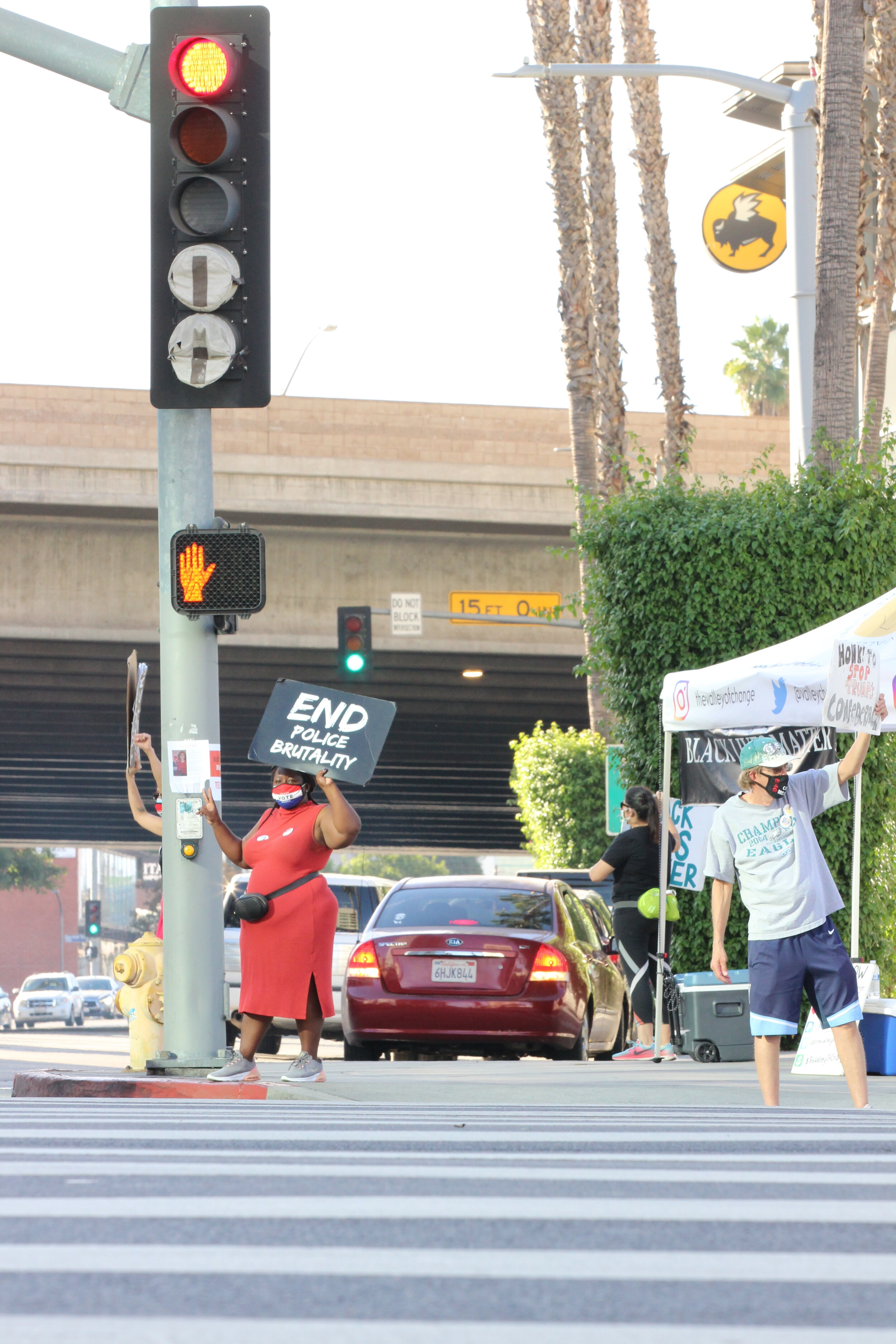   Latoria Green gives out a peace sign to cars as they drive by the corner of Sepulveda Blvd. and Ventura Blvd. in Sherman Oaks, Calif. on Nov. 1, 2020. (Carolyn Burt / The Corsair)  