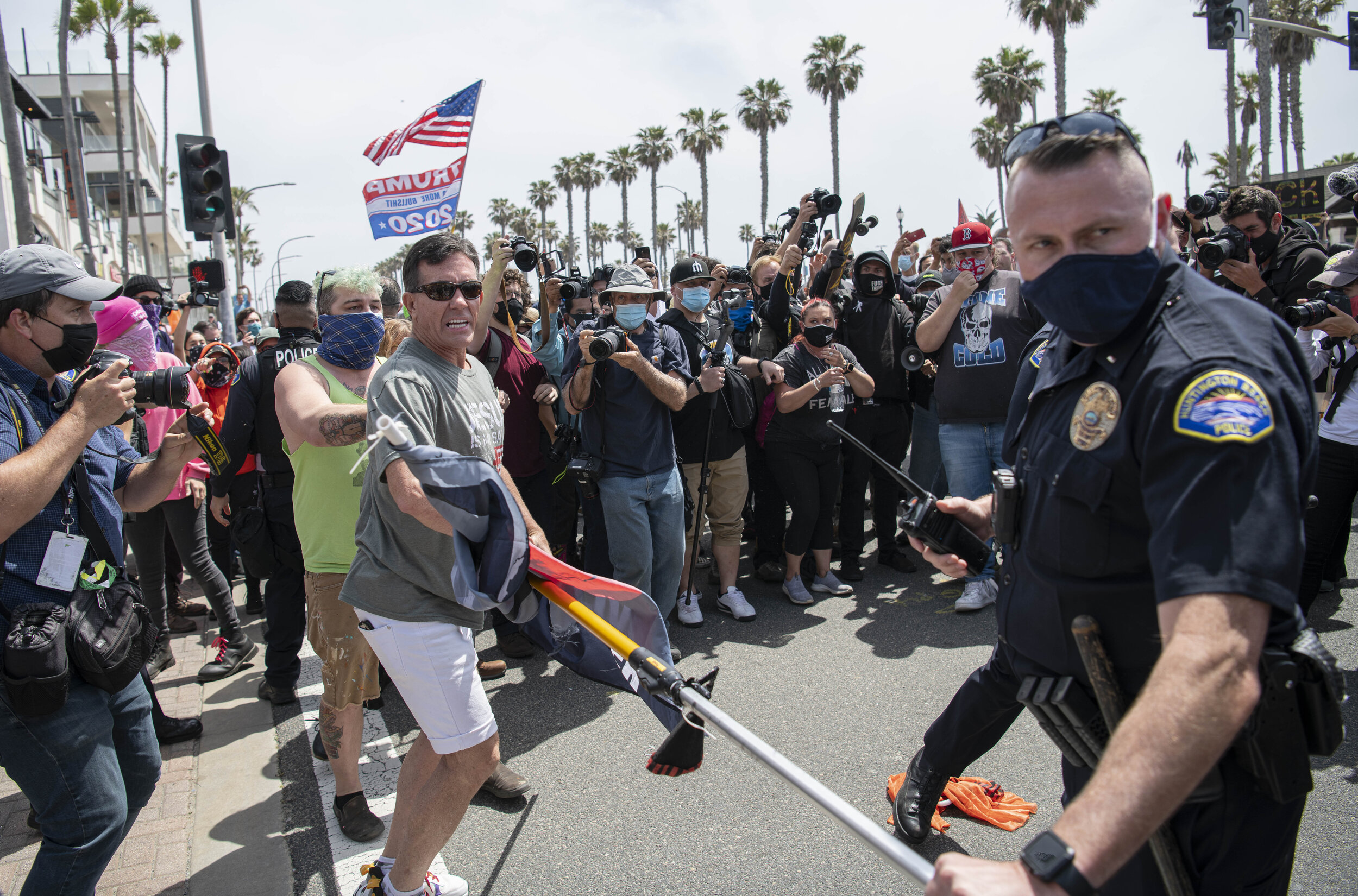  A Protester fights for his flag pole against an angry mob with the assistance of a police officer on March 11, 2021 in Huntington Beach, Calif. at the rally held for Black Lives Matter/ White Lives Matter members. (Jon Putman / The Corsair) 