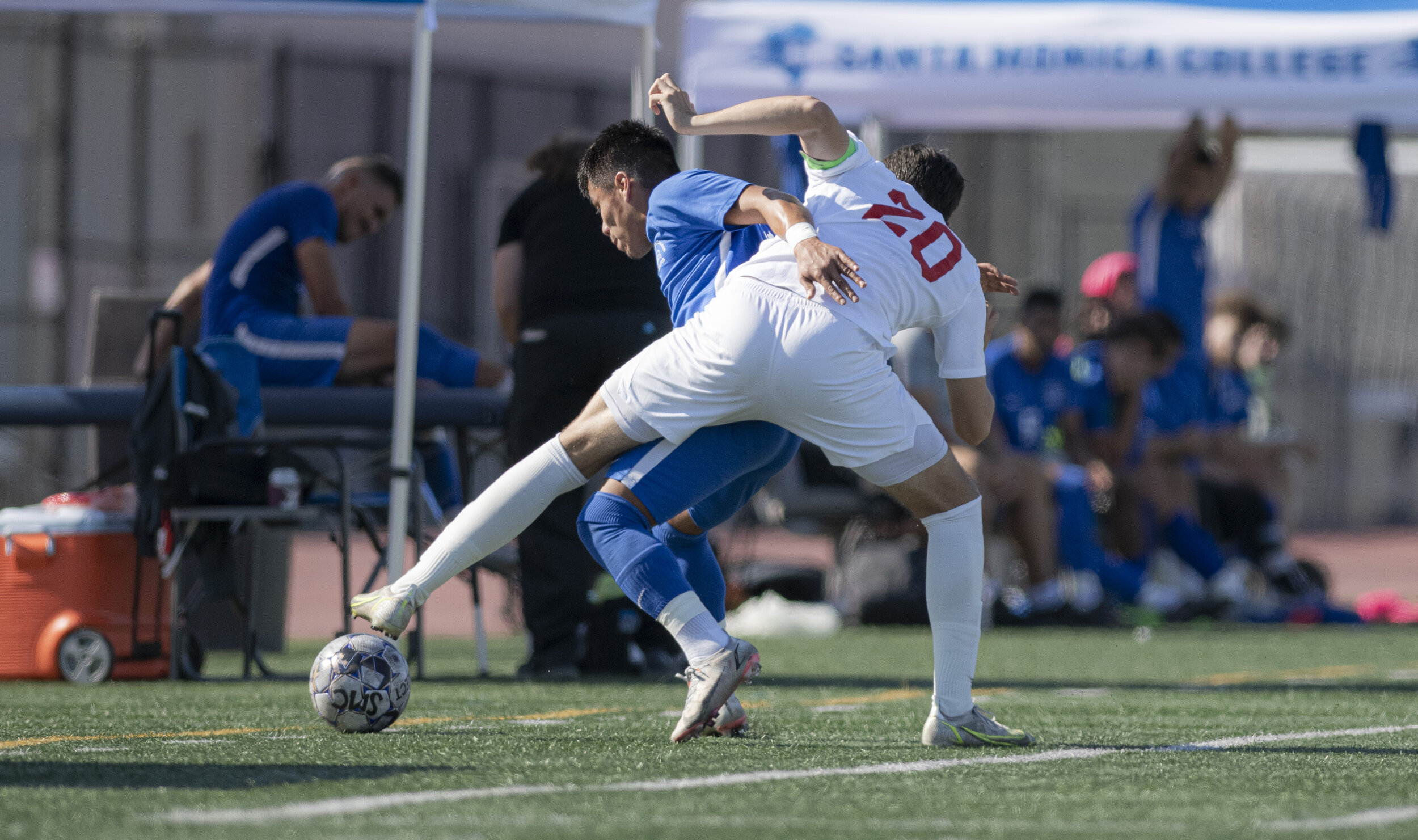  Santa Monica College Corsairs freshman Denilson Garcia (11) holds off a Bakersfield defender as he attempts to take the ball while an injured player sits in the background. (Jon Putman | The Corsair) 