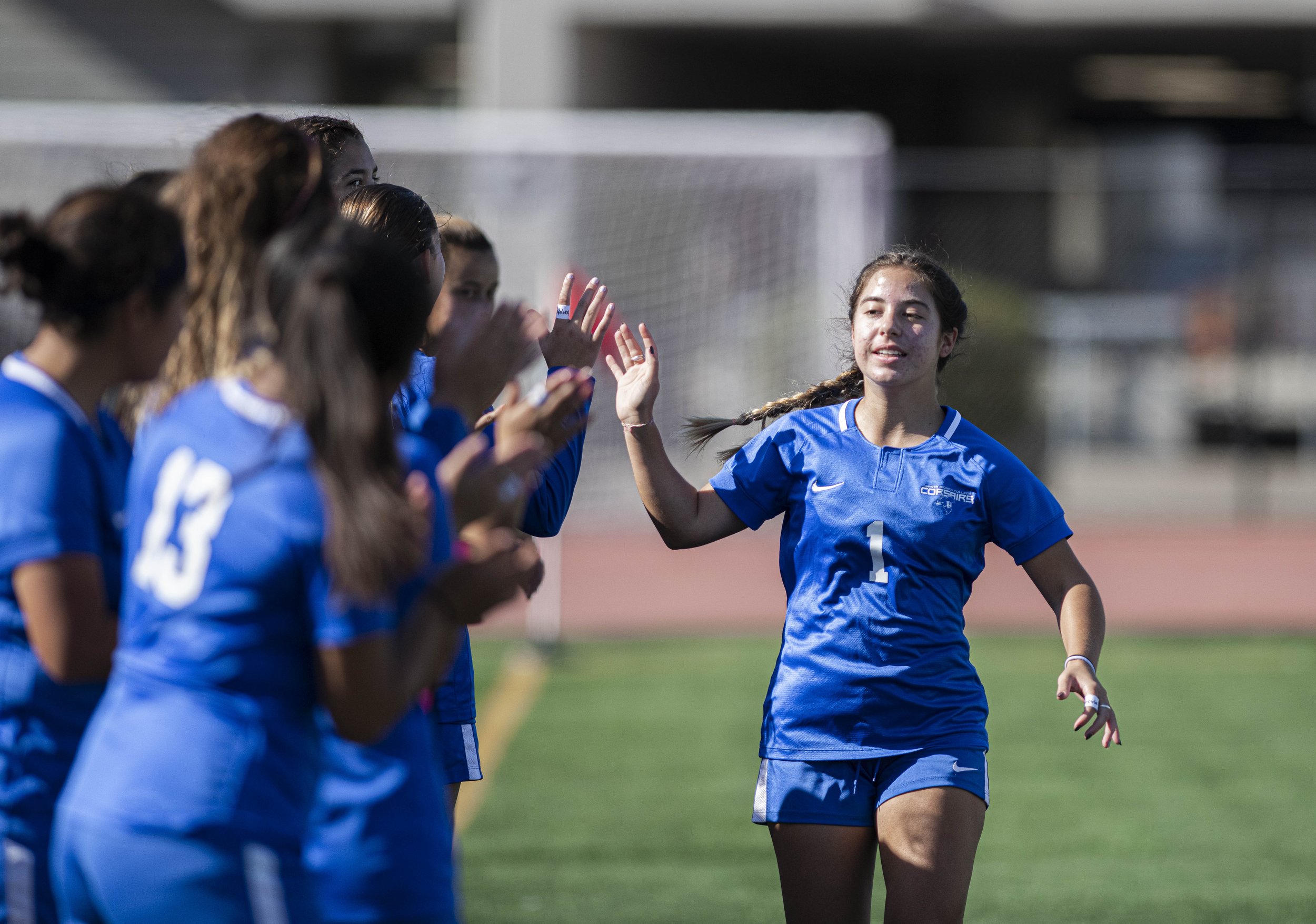  Santa Monica College Corsairs freshman Sophie Doumitt (1) smacks hands with teammates as the starting line ups are announced before the start of the game with LA Valley. (Jon Putman | The Corsair) 