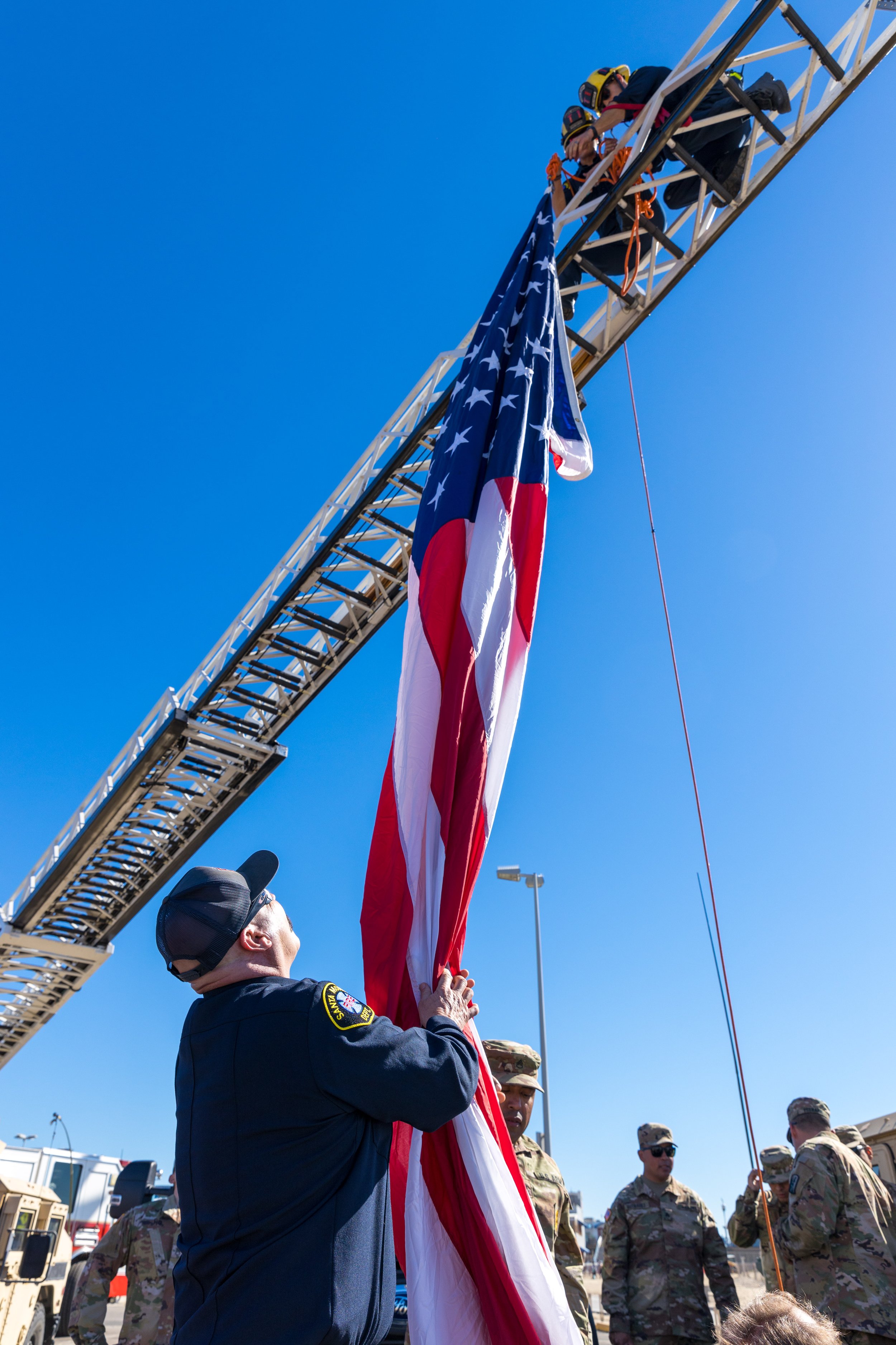  Members of the Santa Monica Fire Department remove a flag from its place hanging from a ladder after the Veterans Day commemoration near the Santa Monica Pier in Santa Monica, California on November 11, 2021. (Maxim Elramsisy | The Corsair) 