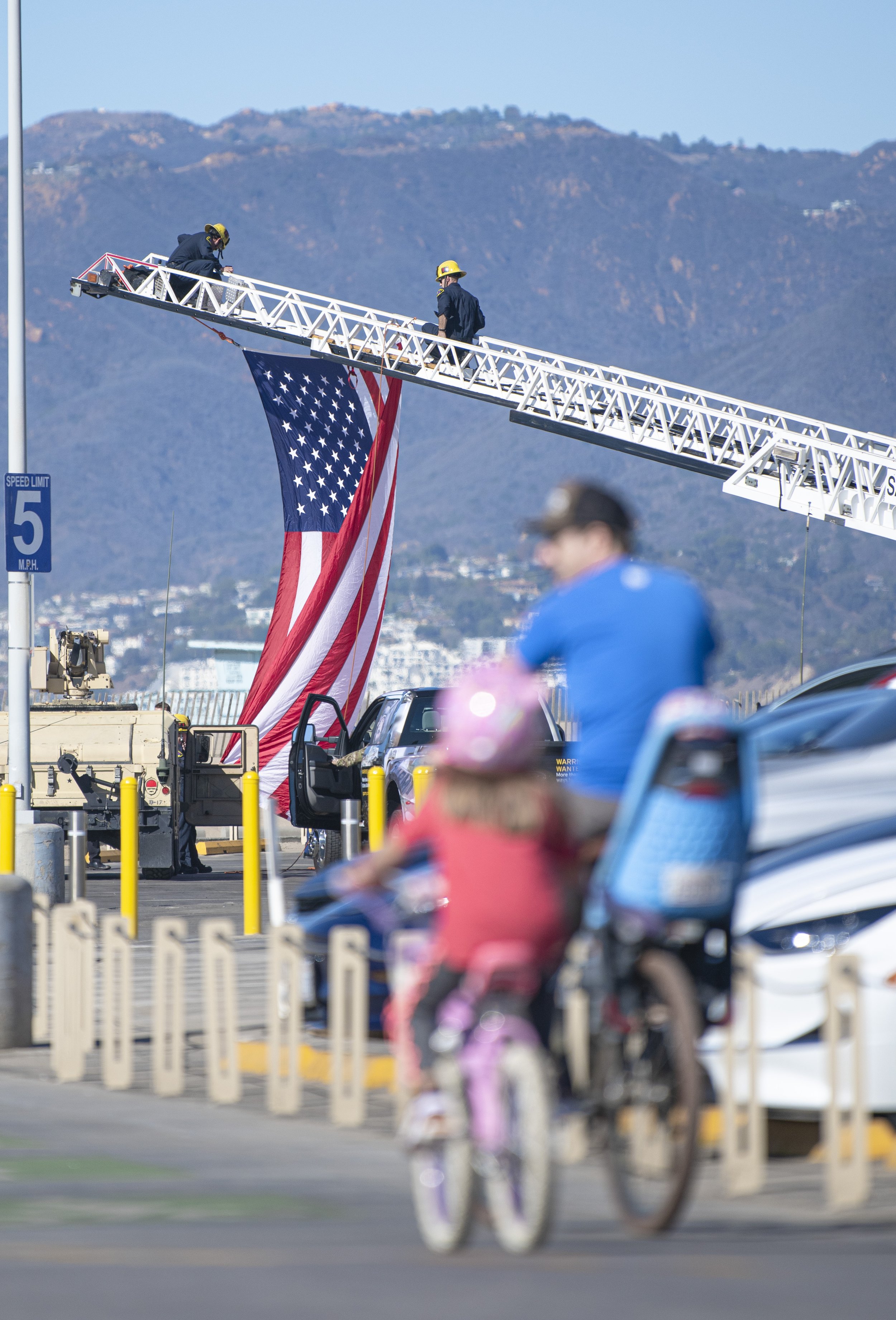  Santa Monica Firefighters can be seen hoisting the American Flag up to their Fire Engine while patrons ride their bikes down the Santa Monica Boardwalk on Nov. 11, 2021 in Santa Monica, Calif. (Jon Putman | The Corsair) 