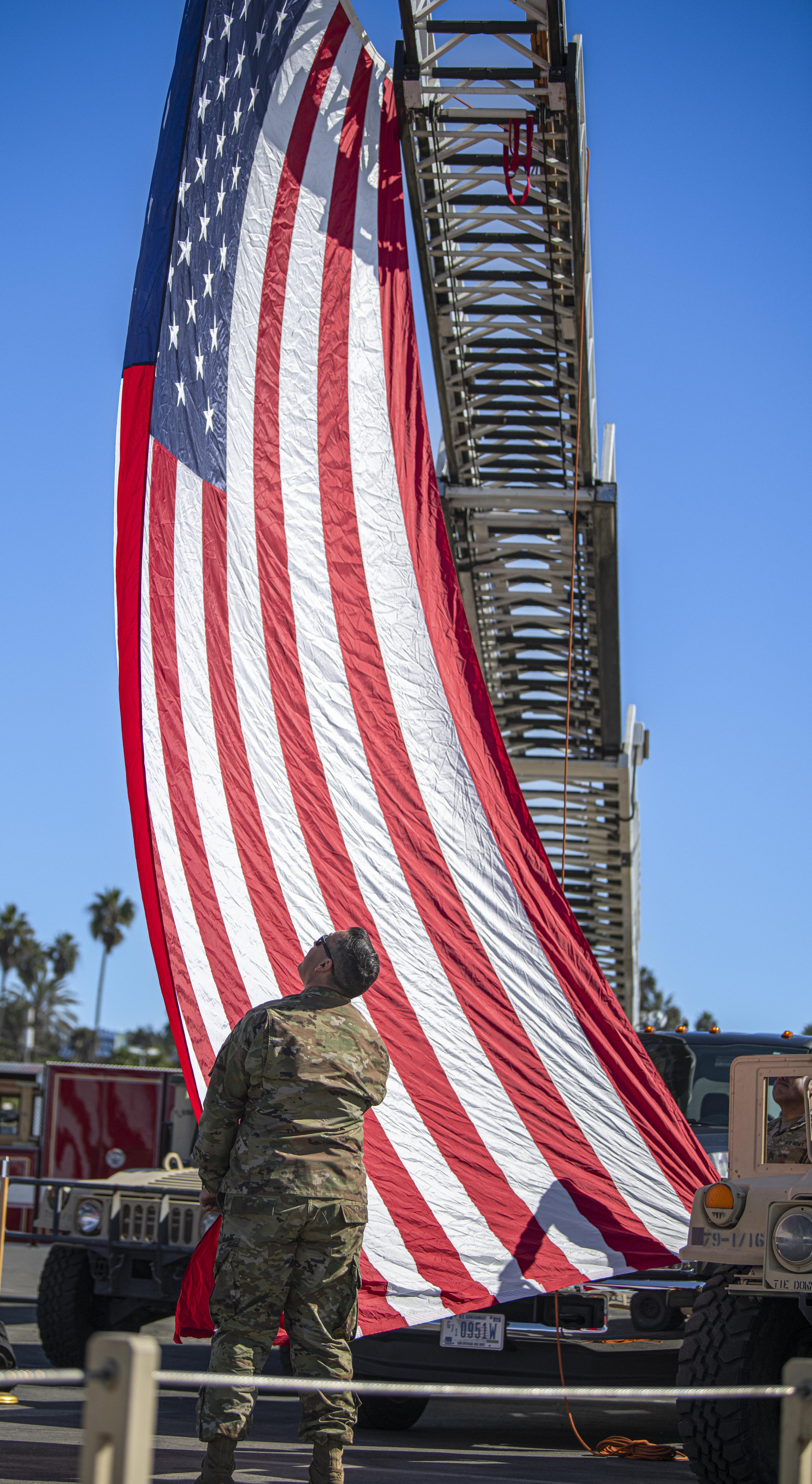  A Califonia National Gaurd soldier  holds the enlarged American flag steady while other soldiers help secure the flag at the Veterans Day event held by both the Los Angeles Army Recruitment Battalion and the California Army National Gaurd on Nov. 11