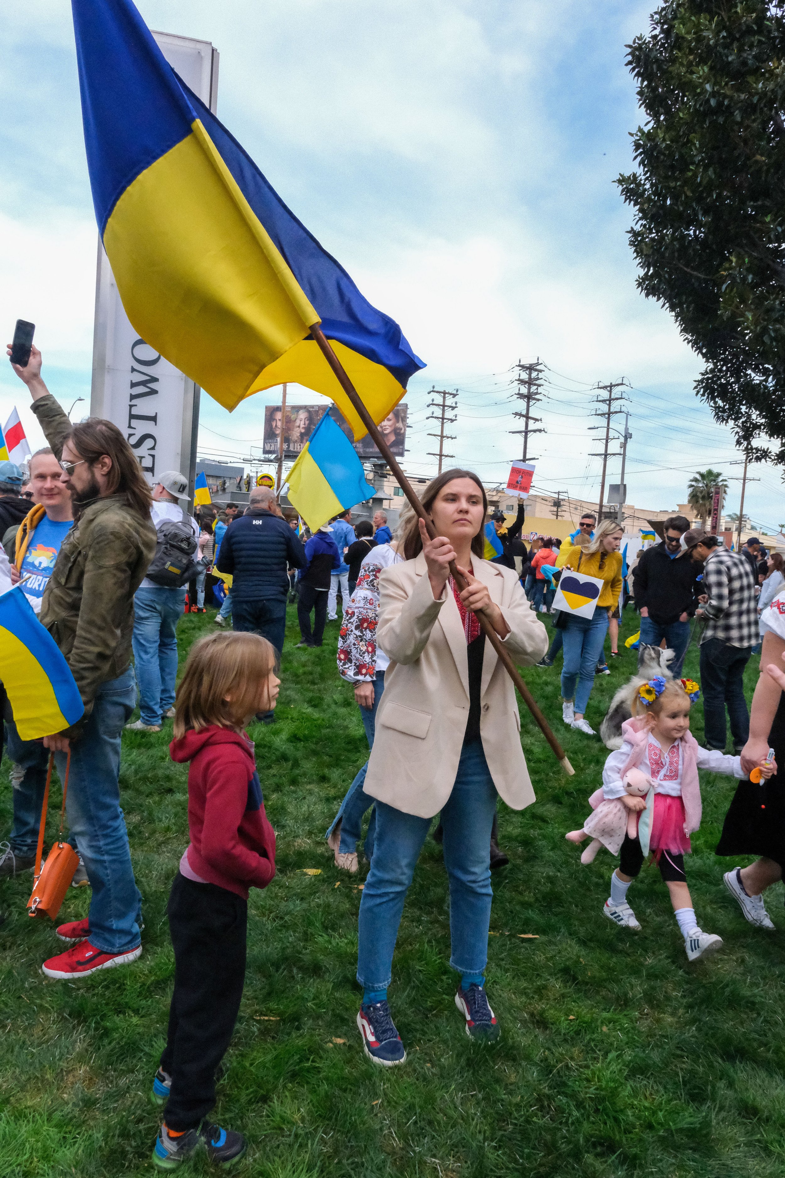  Hanna Husakova waves a Ukrainian flag next to her son, Sascha. Husakova was born in Donetsk, Ukraine, and still has family and friends in Ukraine. She states that “We cannot be silent here in the world. “  Some moms from her son’s school were “suppo