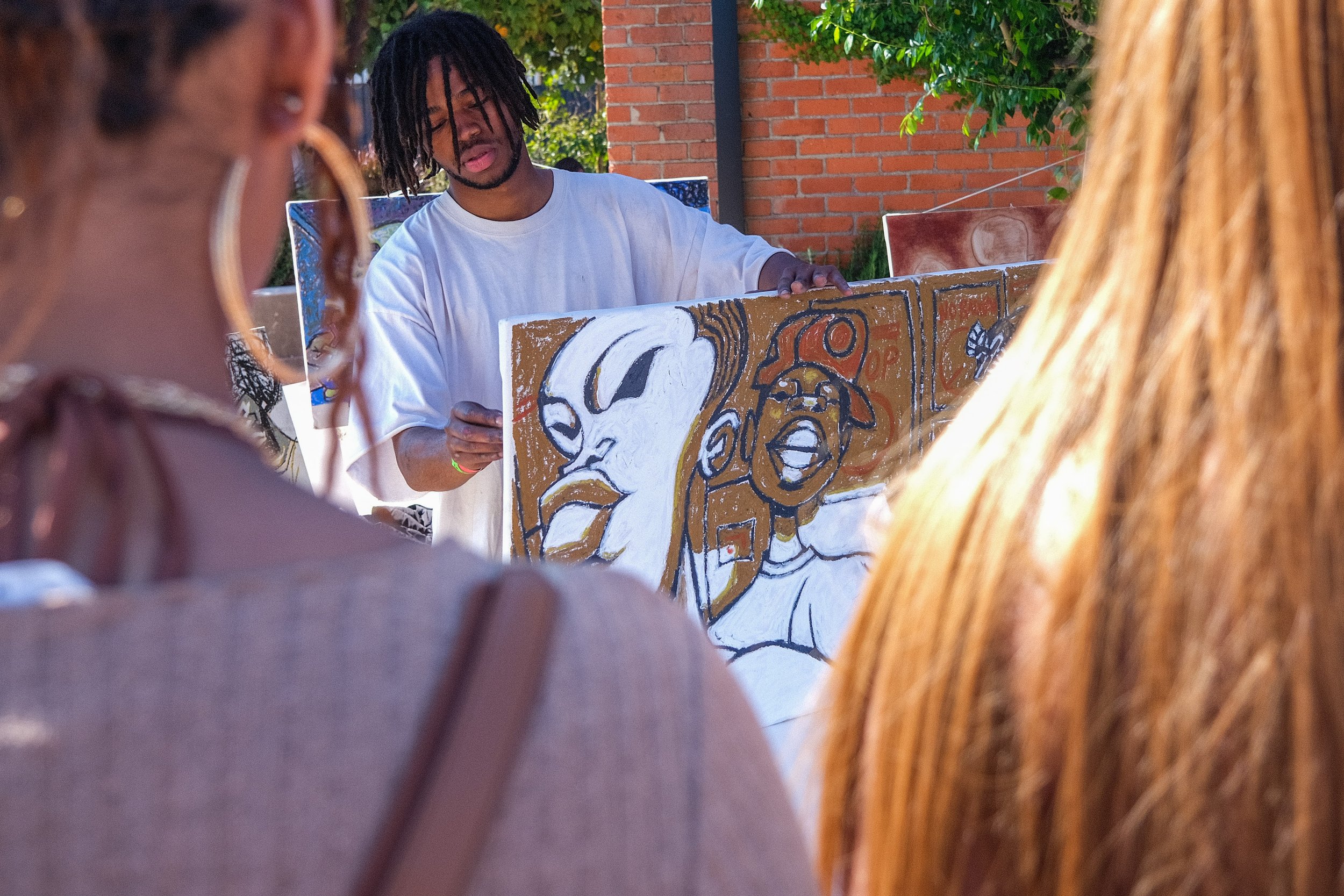  Event-goers watch as Kid Bosco AKA Josiah Davis signs the back of the artwork he finished painting live at the Black Market Flea in Los Angeles, on Sunday, March 27, 2022 (Anna Sophia Moltke | The Corsair) 
