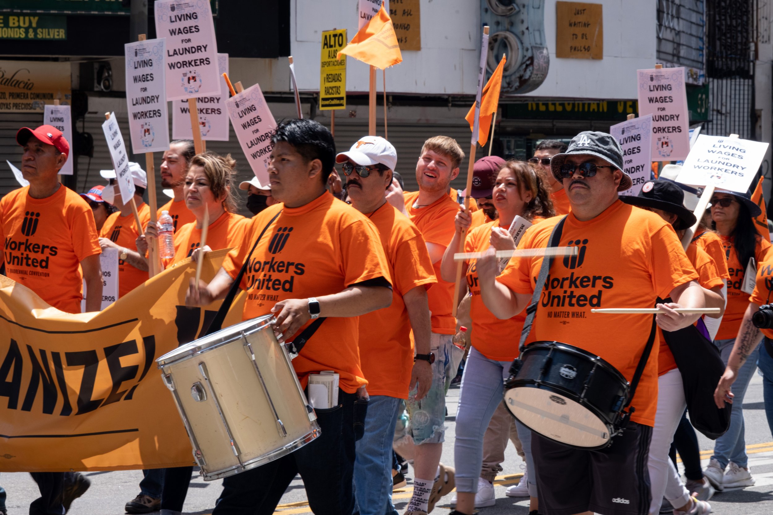  Members of the Workers United labor union pass by, with drummers. Workers United is a labor union that ‘represents about 85,000 workers in the textile, commercial laundry, pharmaceutical, and gaming industries.’ Broadway street in Los Angeles, on Su