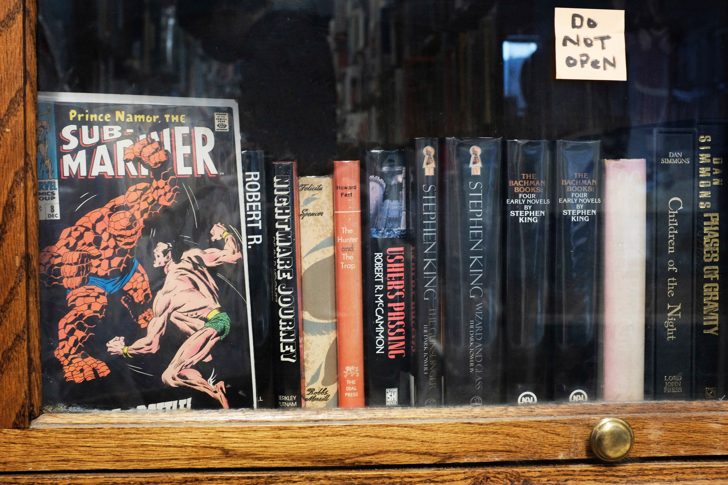  Behind a glass, in a locked book case sit the most rare and expensive books of the store. Featured in this shelf is a Marvel comic book, Prince Namor, The Sub Mariner, which is in mint condition. Next to the comic are novels by Stephen King and Dan 