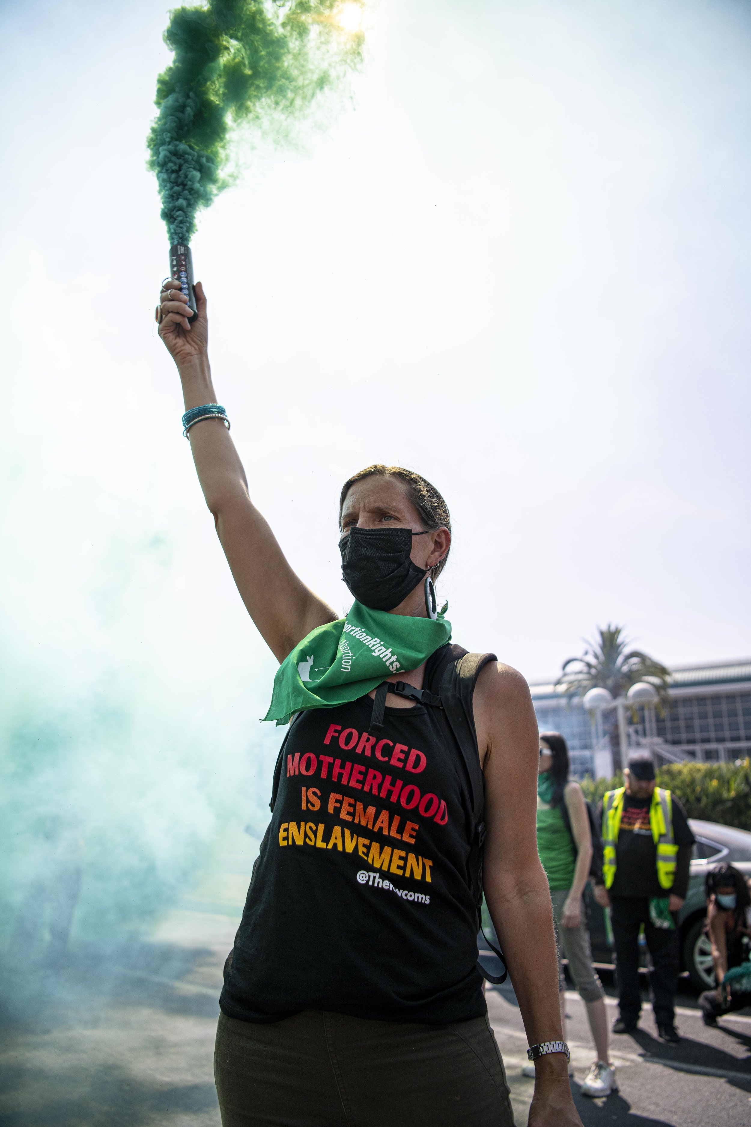  A Rise Up for Abortion Rights member holds up a green smoke bomb in front of police to show their support for Abortion rights. (Jon Putman | The Corsair) 