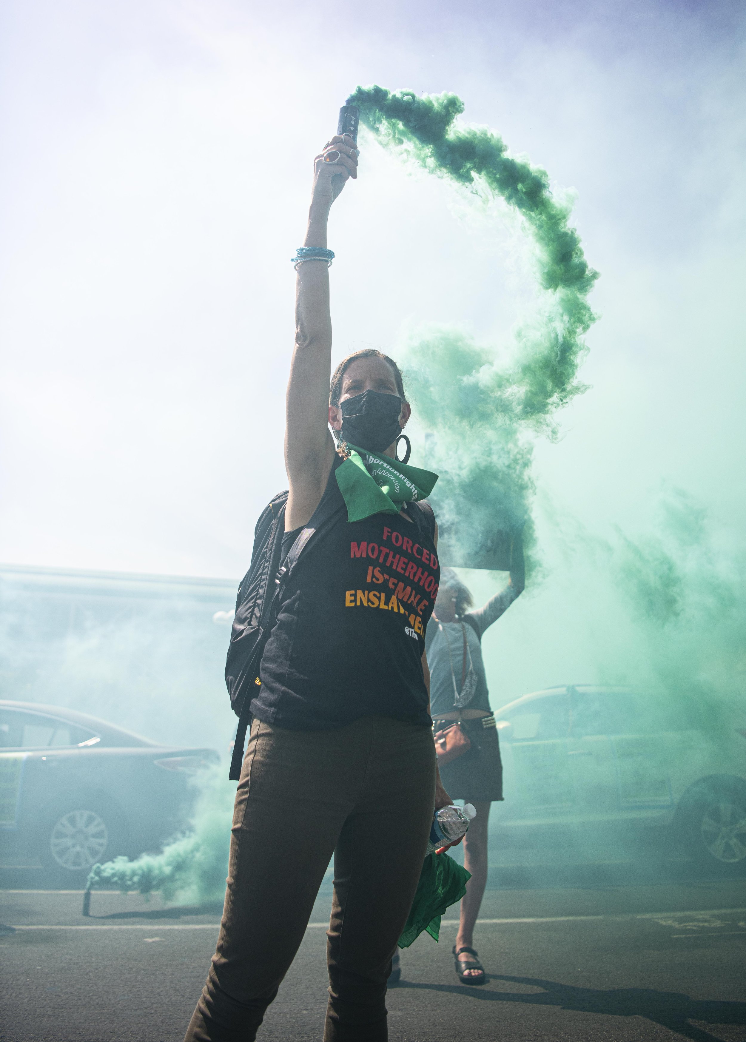  A Rise Up for Abortion Rights member holds up a green smoke bomb in front of police to show their support for Abortion rights. (Jon Putman | The Corsair) 