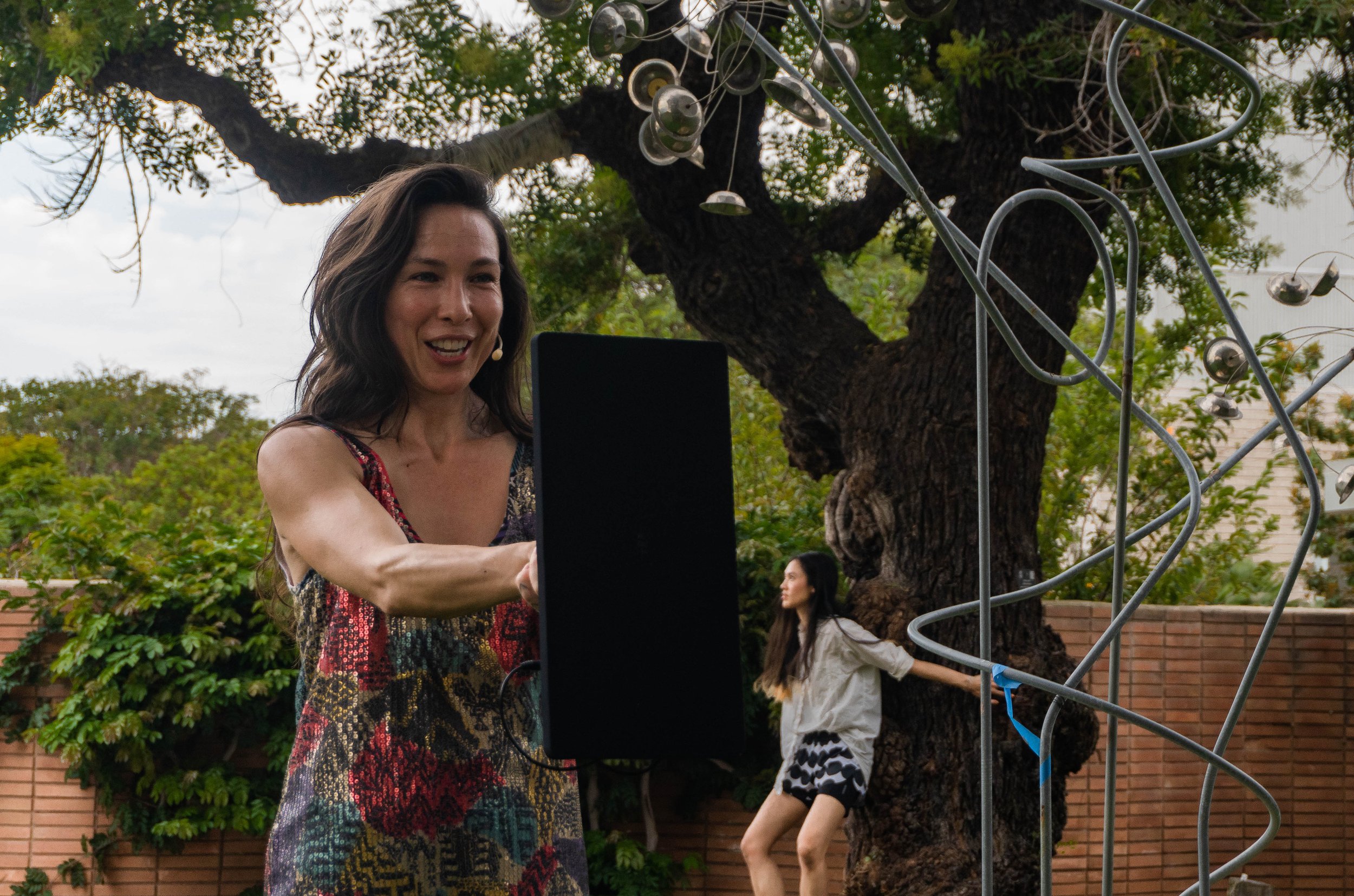  Emily Johnson, Native Alaskan artist of Yupik descent, choreographer and artistic director of Catalyst whispers and holds a speaker before her audience, while Sugar Vendil, Catalyst performer performs the third and final  around the courtyard of San