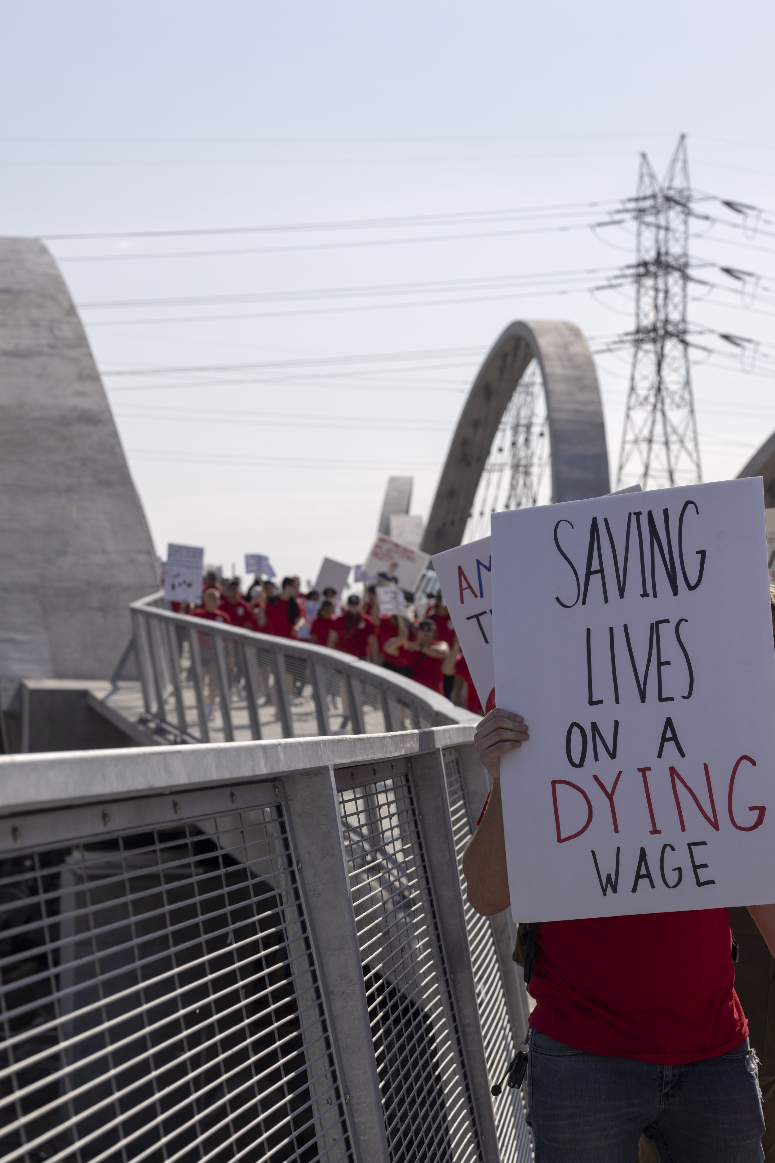  EMS workers from Los Angeles to the Antelope Valley marching over the sixth street bridge into downtown Los Angeles with their signs and red shirts for the march for fair wages. American Medical Response has told the workers they have given their "l