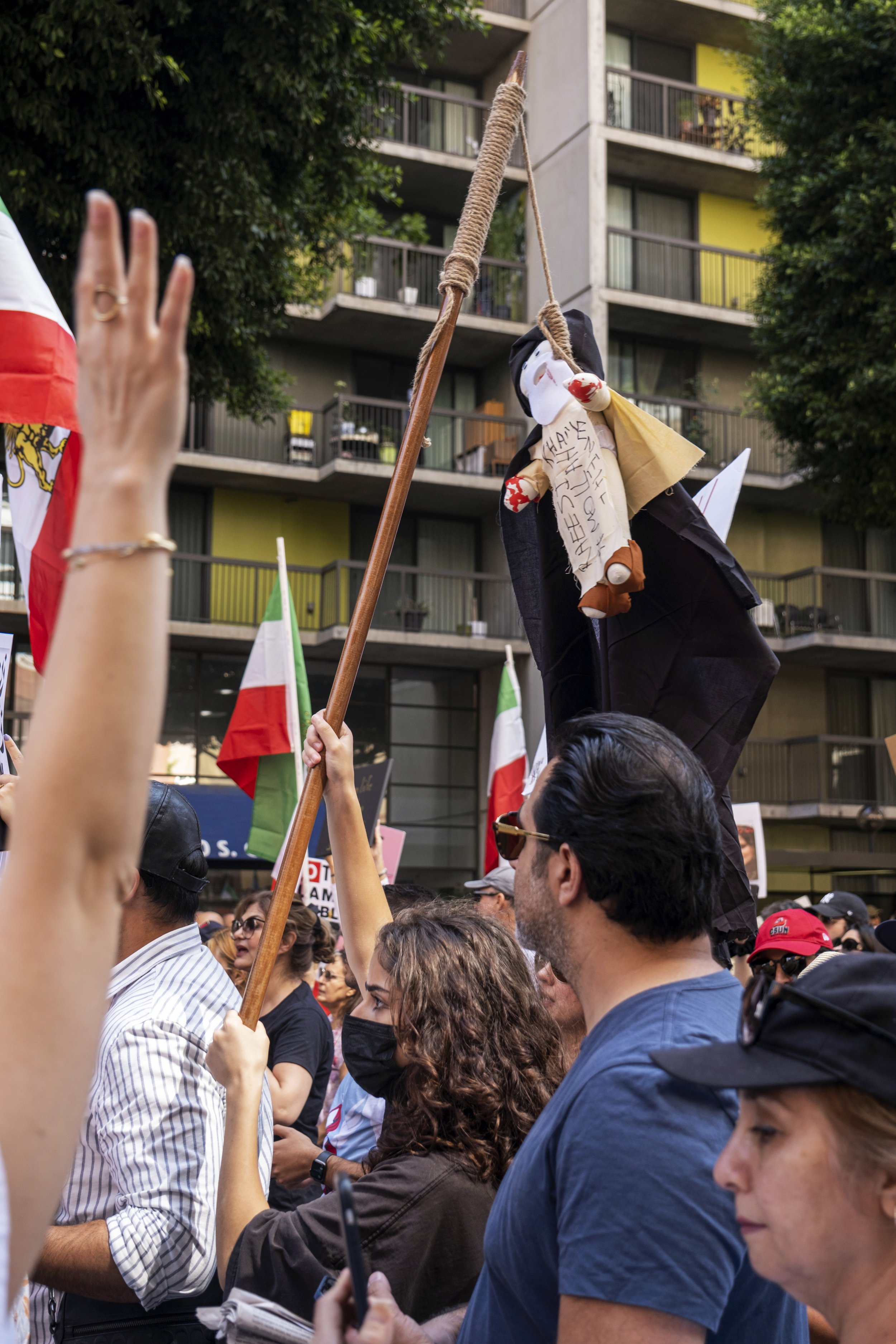 Woman holds a wooden pole, with a doll hanging from a tied rope. The doll whose hands are painted red, has the names of the Freedom Supreme Leader and the President of Iran, with the hashtag Mollah, written on its garb, at the Freedom Rally for Iran