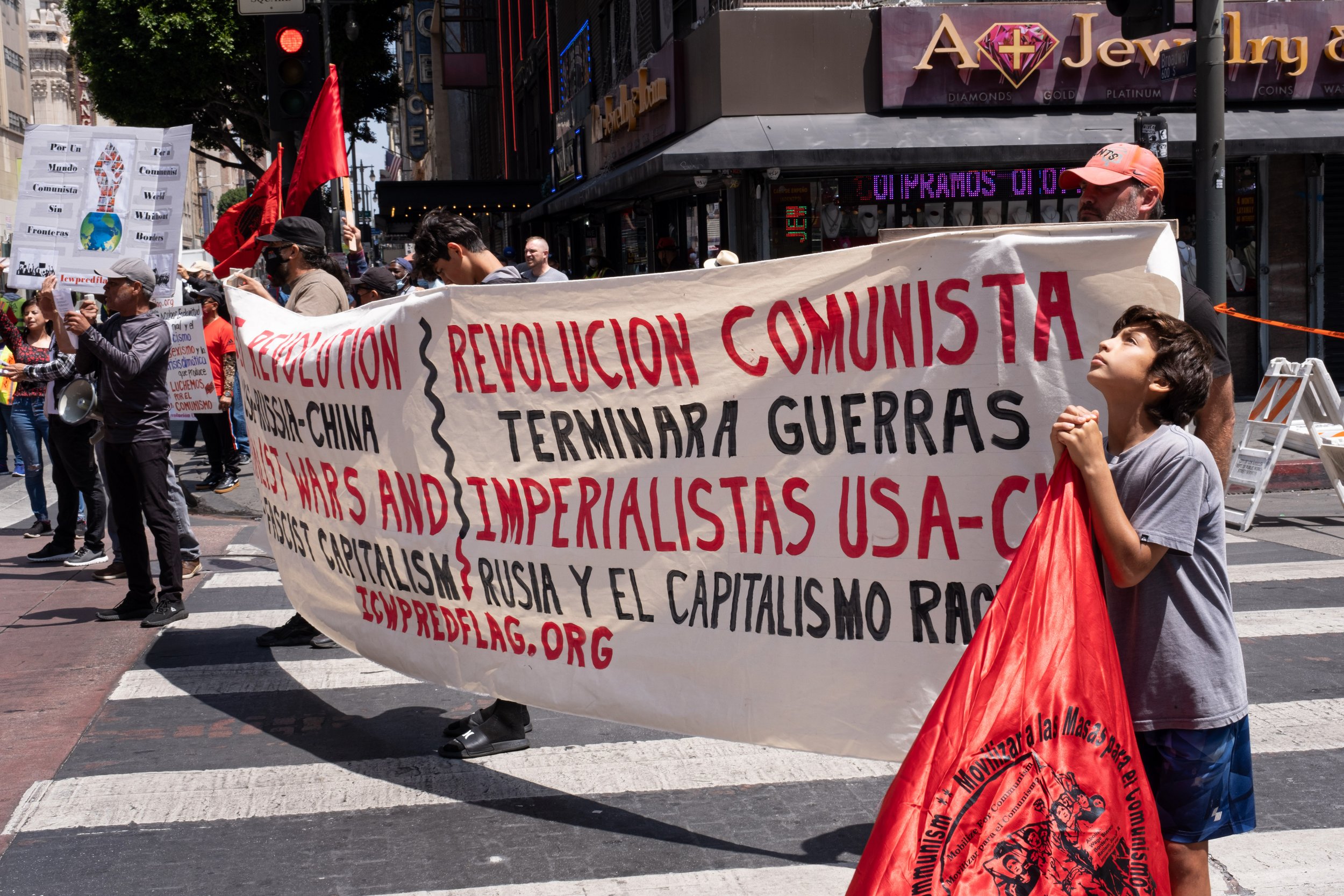  Members of the International Communist Workers Party hold a large sign, facing the crowd that marches down Broadway street in Los Angeles, on Sunday, May 1, 2022. (Anna Sophia Moltke | The Corsair) 