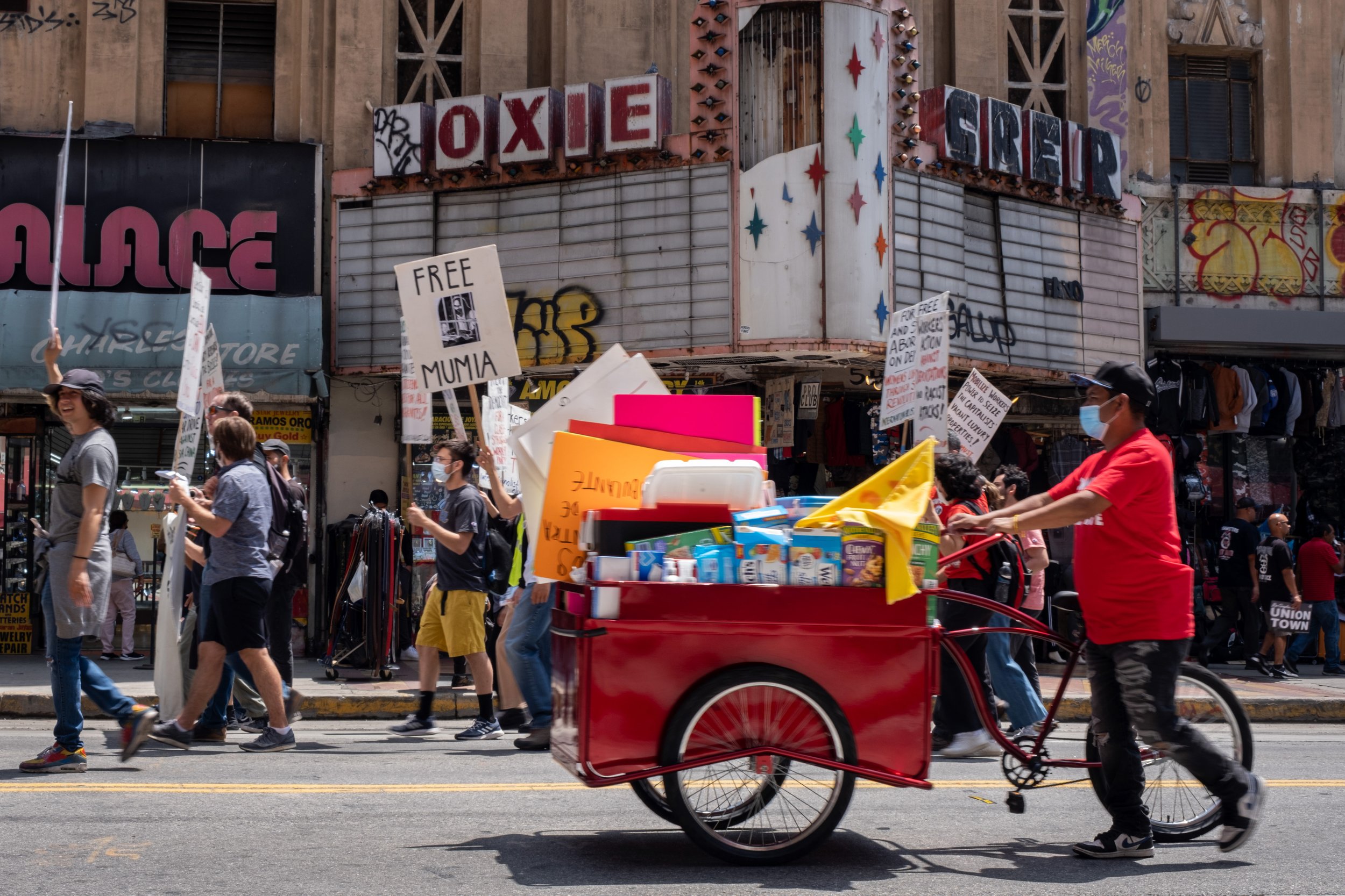  The May Day March leads the crowd and vendors past abandoned buildings such as the Roxie Theatre on Broadway street in Los Angeles, on Sunday, May 1, 2022. (Anna Sophia Moltke | The Corsair) 