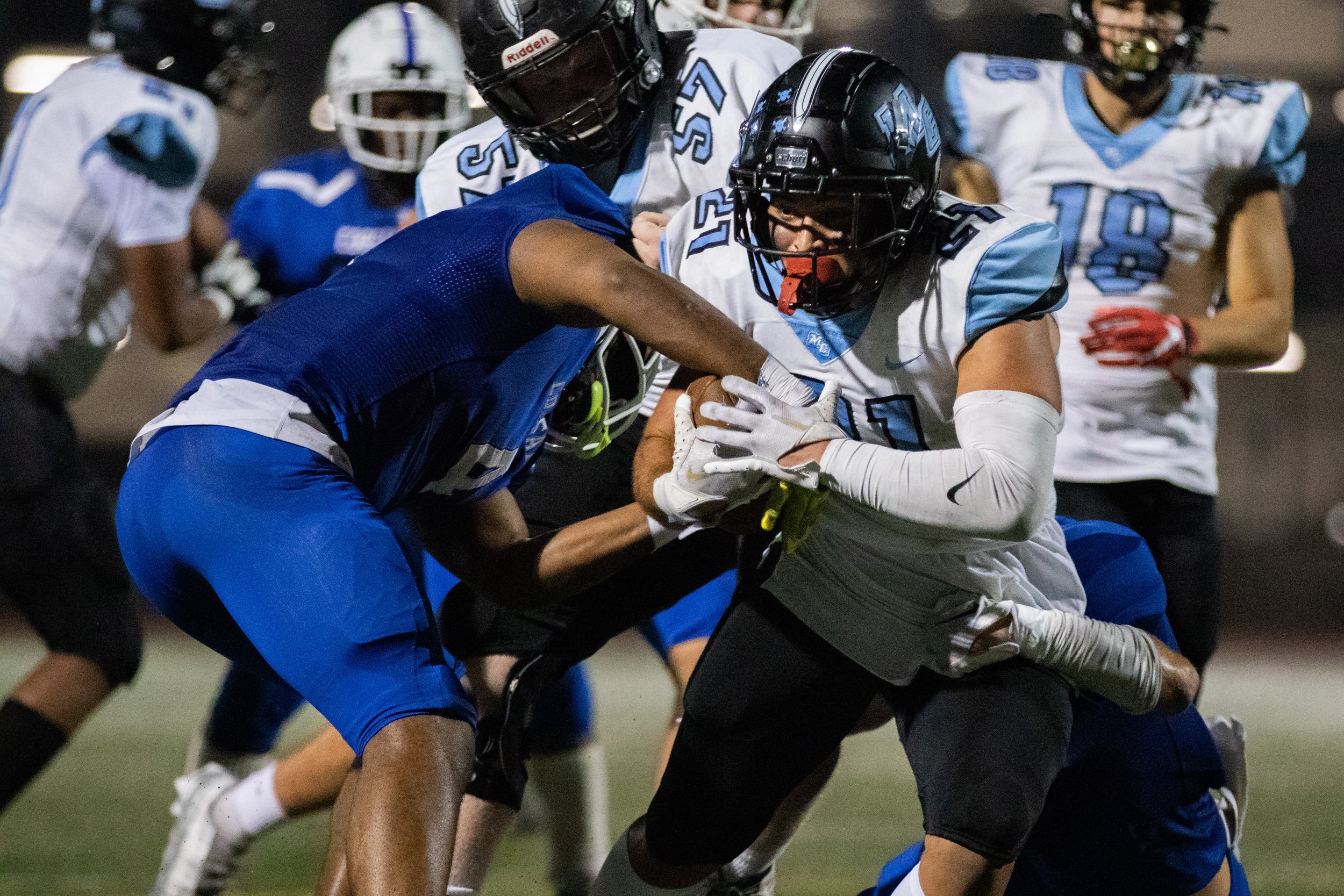  Santa Monica College Corsair linebacker Raejion Baker (4, left) attempting to grab the ball from Moorpark College Raider runningback Gabe Landless (21, right), who is also being tackled by Corsair defensive back Maximillian Palees (11), during the s