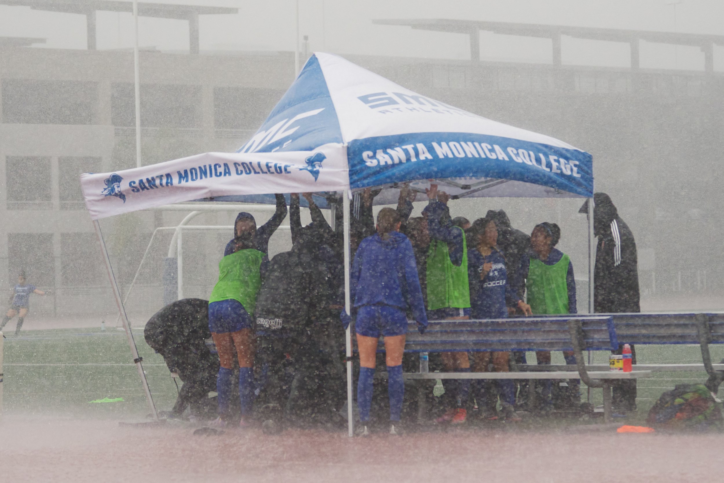 The Santa Monica College Corsairs Women's Soccer team huddles under and holds down their tent during a sudden rainstorm before the match against the Citrus College Owls on Tuesday, Nov. 8, 2022, at Corsair Field in Santa Monica, Calif. The Corsairs 