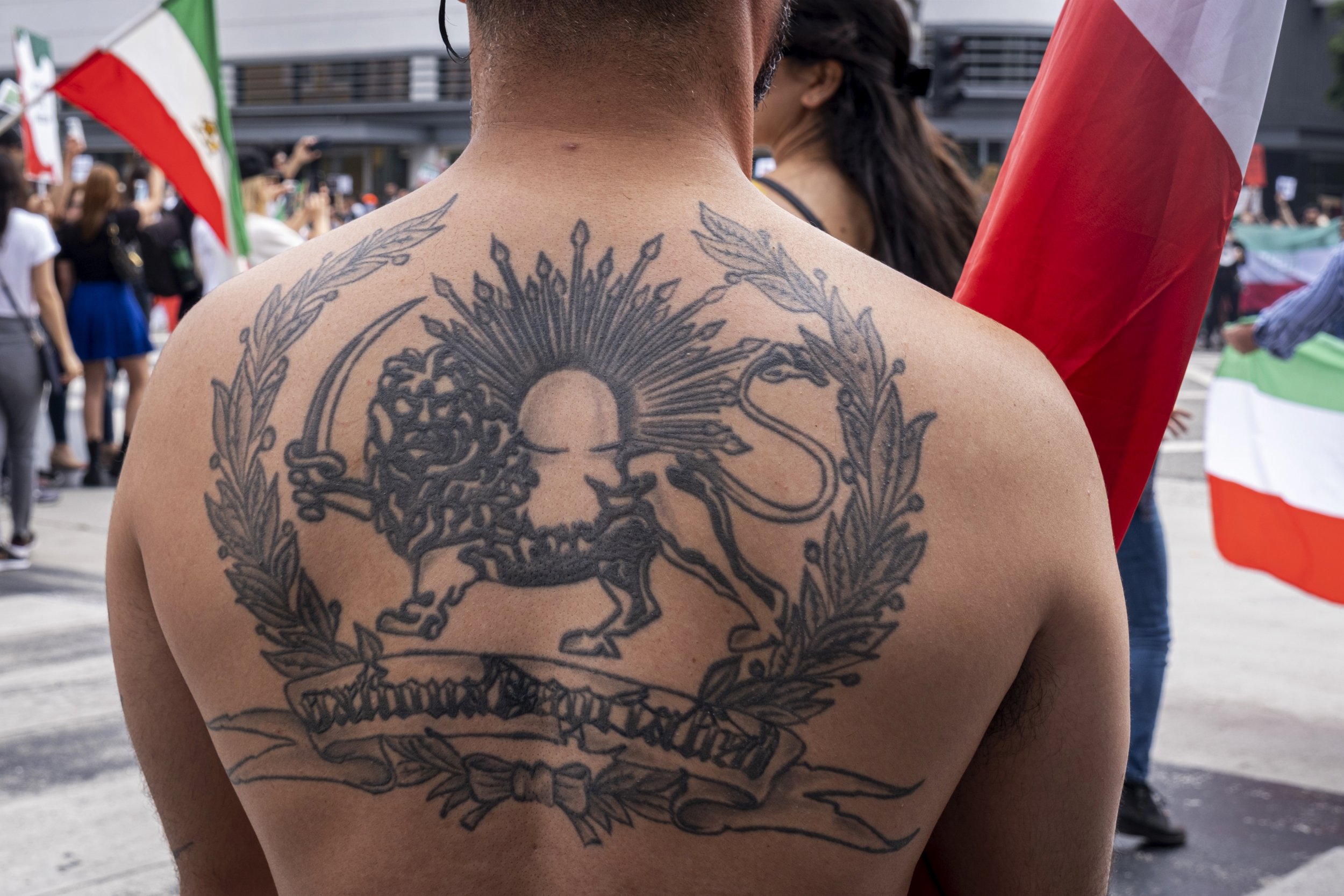  Tattoo of the lion and sun symbol, which sits in the middle of the Iranian flags. This symbol was changed with the new regime, so as protestors call for a regime change, they carry the flag with this symbol. March for Iran at Third Street Promenade 