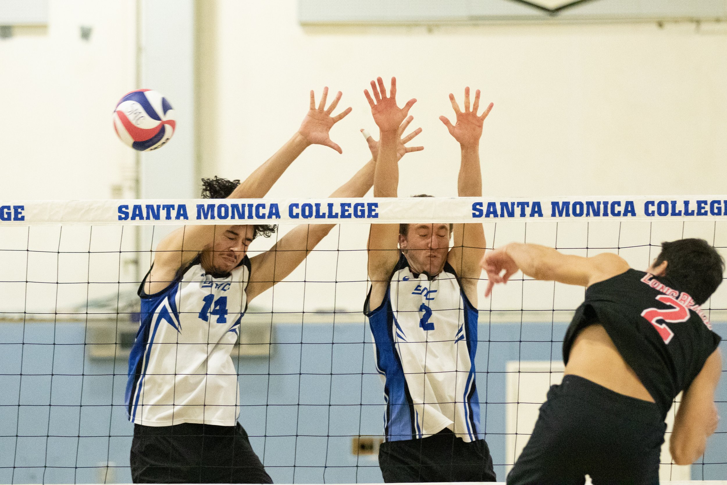  Santa Monica College Corsairs opposite Luis Garzon (14, left) and outside hitter Kane Schwengel (2, center) attempting to block a spike by Long Beach City College Viking Georgi Binev (2, right) during the third set of a home game in Santa Monica, Ca