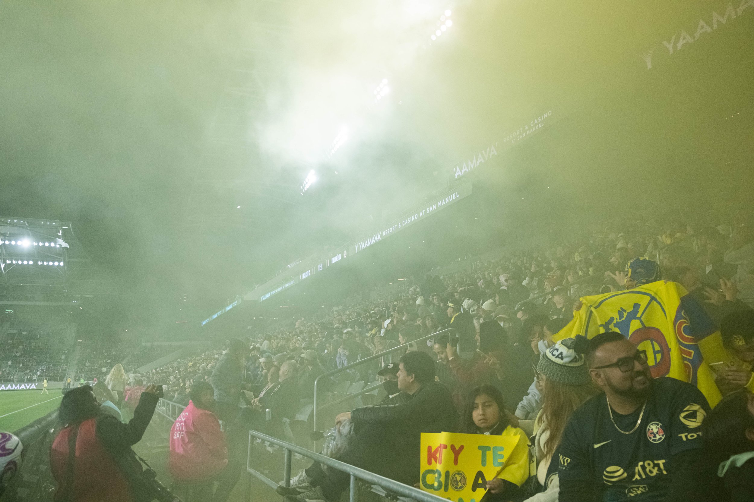 Angel City Football Club and Club America Femenil fans inside a cloud of yellow smoke released by fans from the second floor seats followed by a small parade of spark like fireworks on Wed. March 8 , 2023 at BMO Stadium in Los Angeles, Calif. (Danil