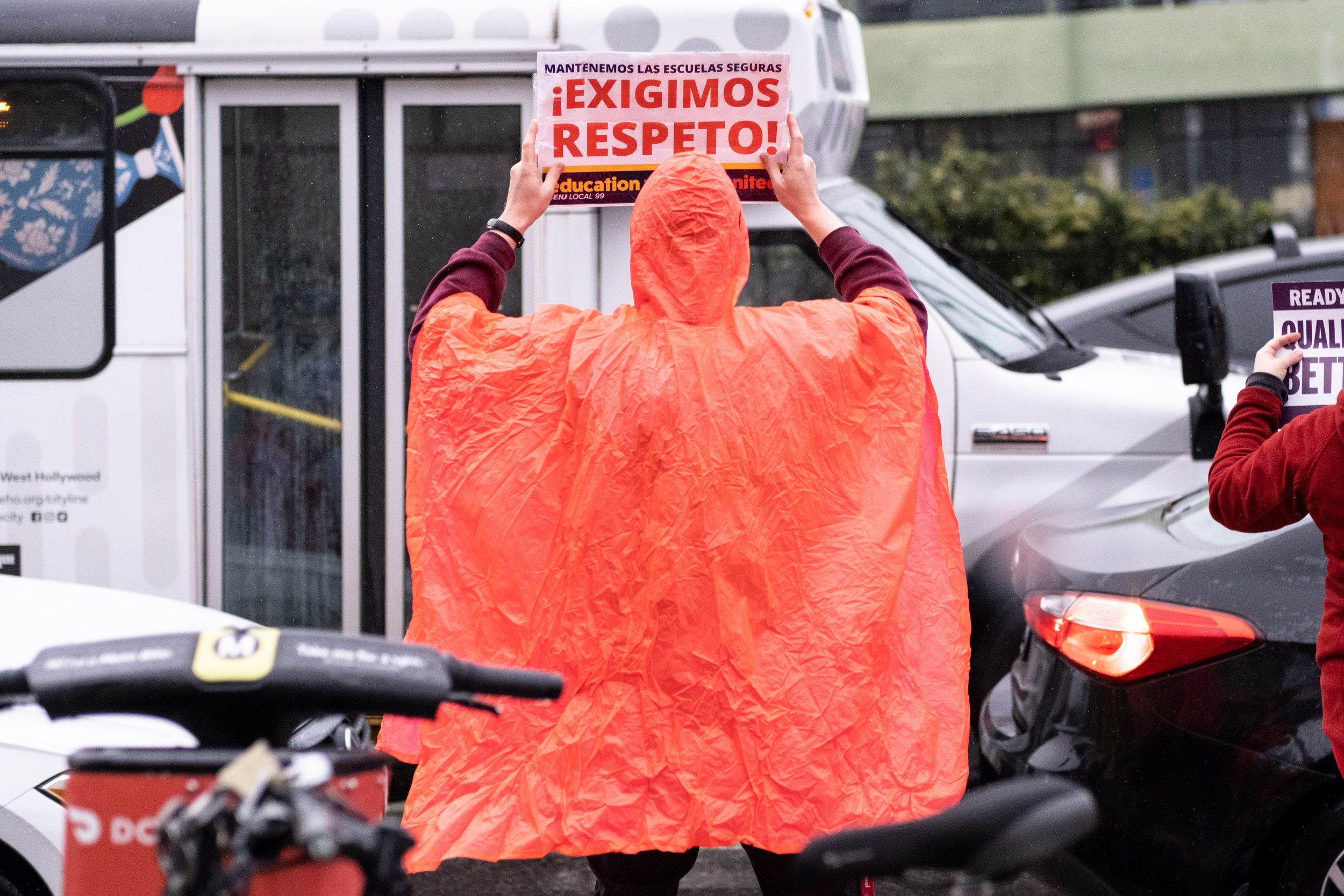  A protester in a bright orange poncho stands in the rain, holding a sign supporting Los Angeles Unified School District staff while on strike in front of Hollywood High School, in Los Angeles, Calif. on Tuesday, March 21, 2023. (Akemi Rico | The Cor