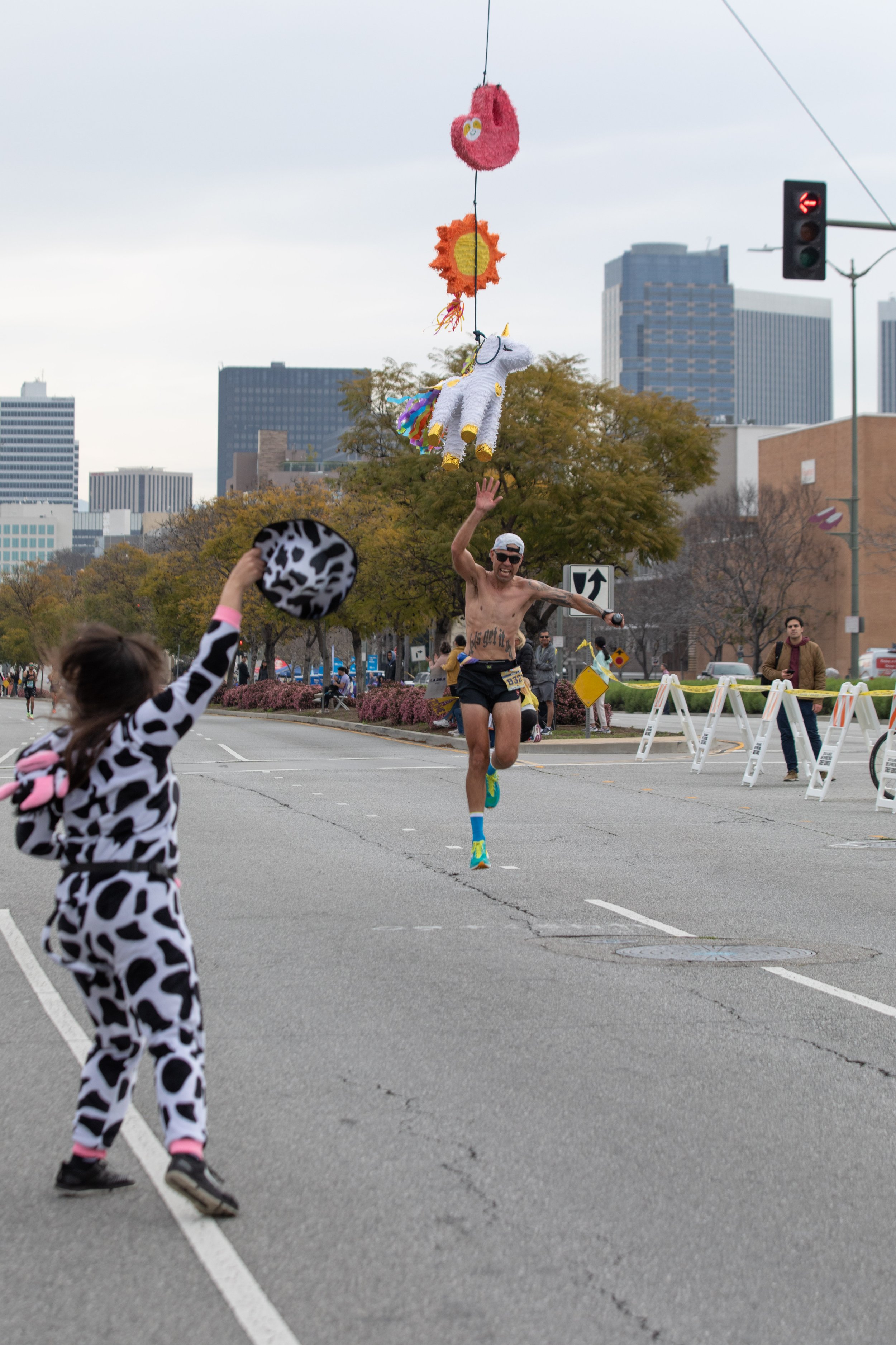  Aracely Rodriguez wearing a cow outfit jumps on excitement when a runner hits the piñata on mile 19 during the L.A. Marathon 2023. Sunday, March 19, 2023. Los Angeles, Calif. (Jorge Devotto | The Corsair) 