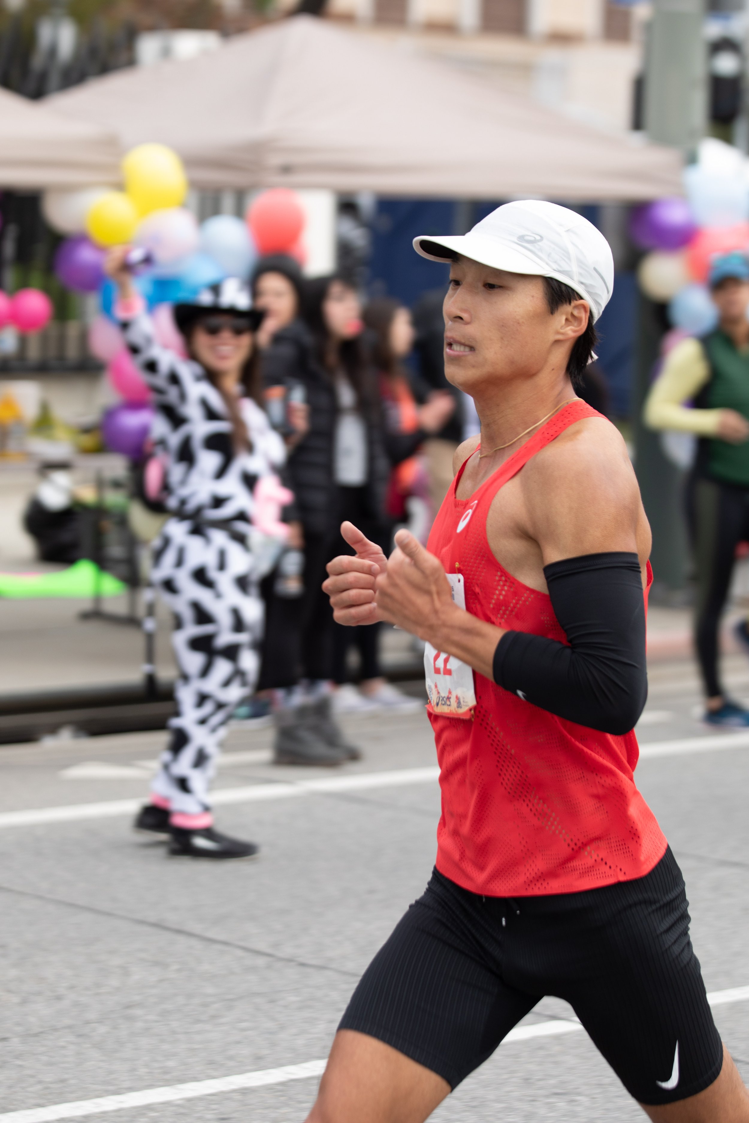  American Jason Yang from Los Angeles running on Santa Monica Blvd. heading West passing through the Valley Runners Club cheers of Aracely Rodriguez (back) on mile 19 during the L.A. Marathon 2023. Yang crossed the line in nineth place on Sunday, Mar