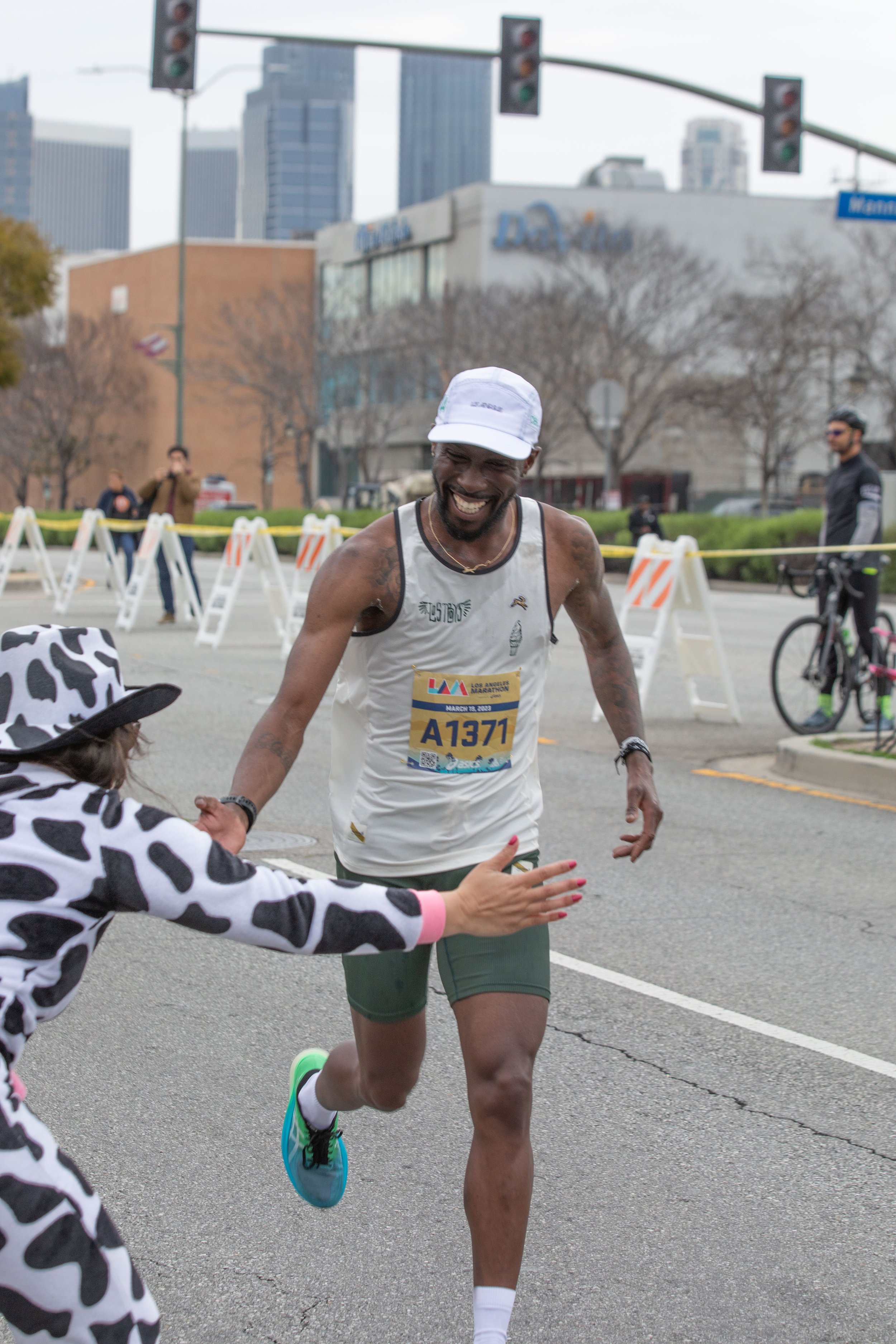  Aracely Rodriguez (wearing a cow outfit) from the cheering group of Valley Runners Los Angeles about to high five Marquis Bowden on mile 19 during the L.A. Marathon 2023. Sunday, March 19, 2023. Los Angeles, Calif. (Jorge Devotto | The Corsair) 