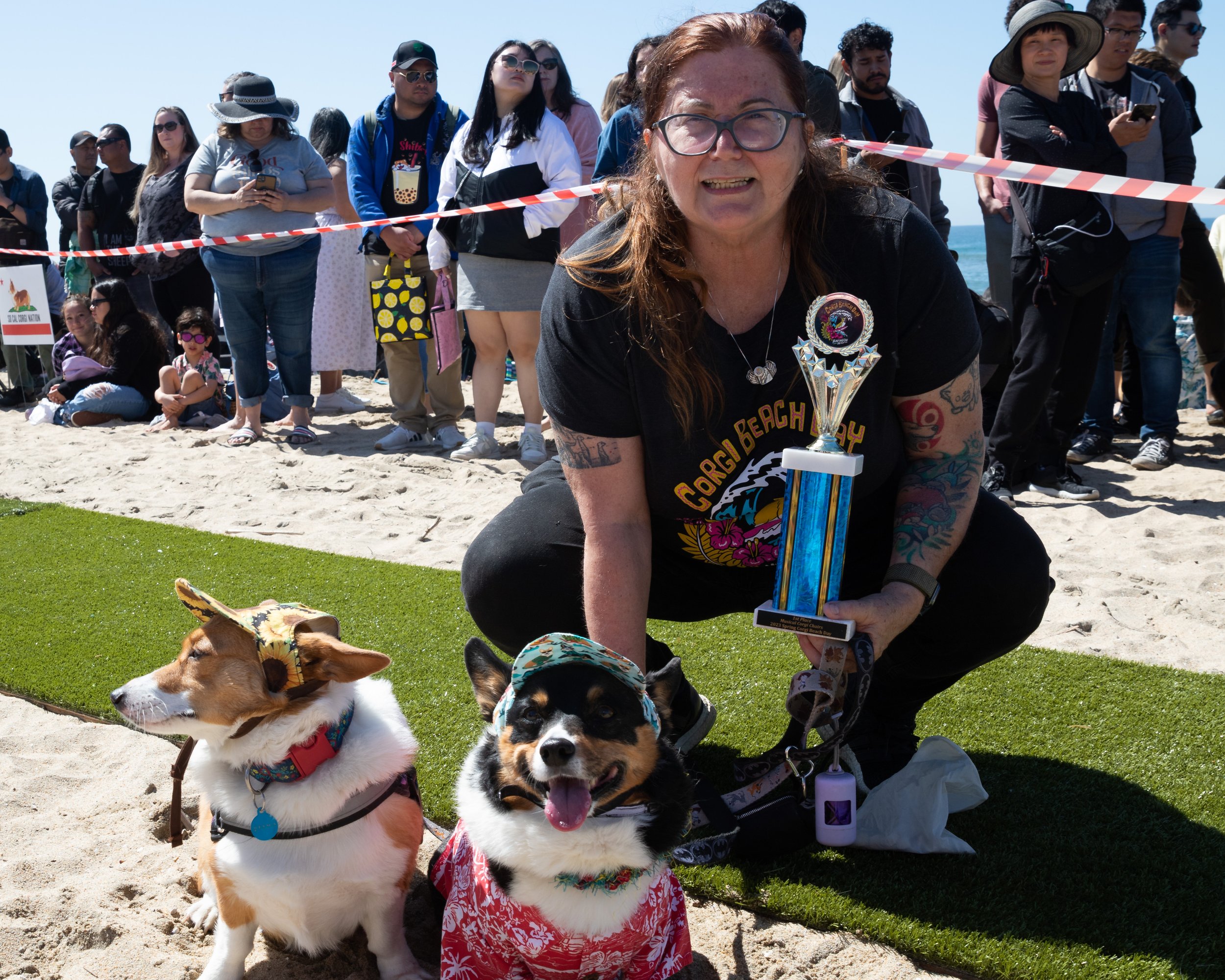  Cynthia Lasley (R-L), Kilo, and Coco pose with the trophy Lasley and Kilo won in the Corgi Musical Chairs during Corgi Beach Day at Huntington Dog Beach, Huntington Beach, Calif., on Saturday, April 1, 2023. There were over a thousand people in atte