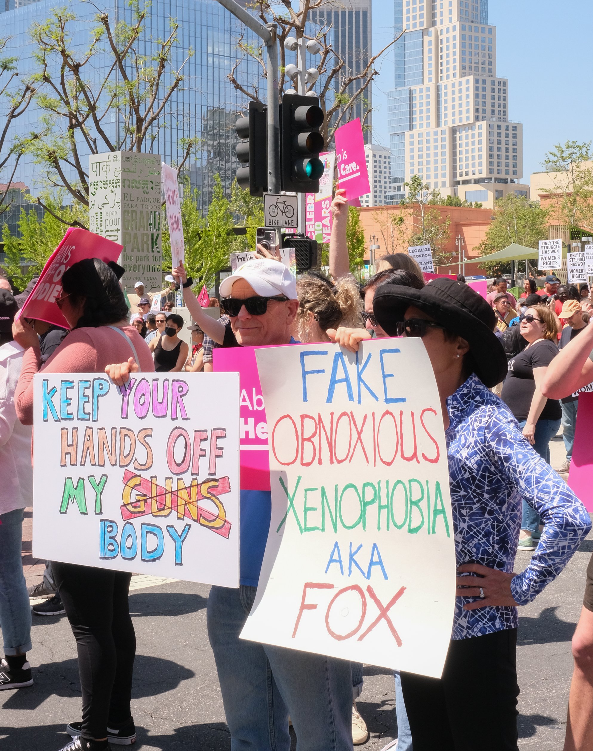  Demonstrators Craig Winterman(left) and May Lee (right) are holding up signs at women’s March Foundations ceremony at Los Angeles City Hall. April 15,2023 (Alejandro Contreras | The Corsair) 