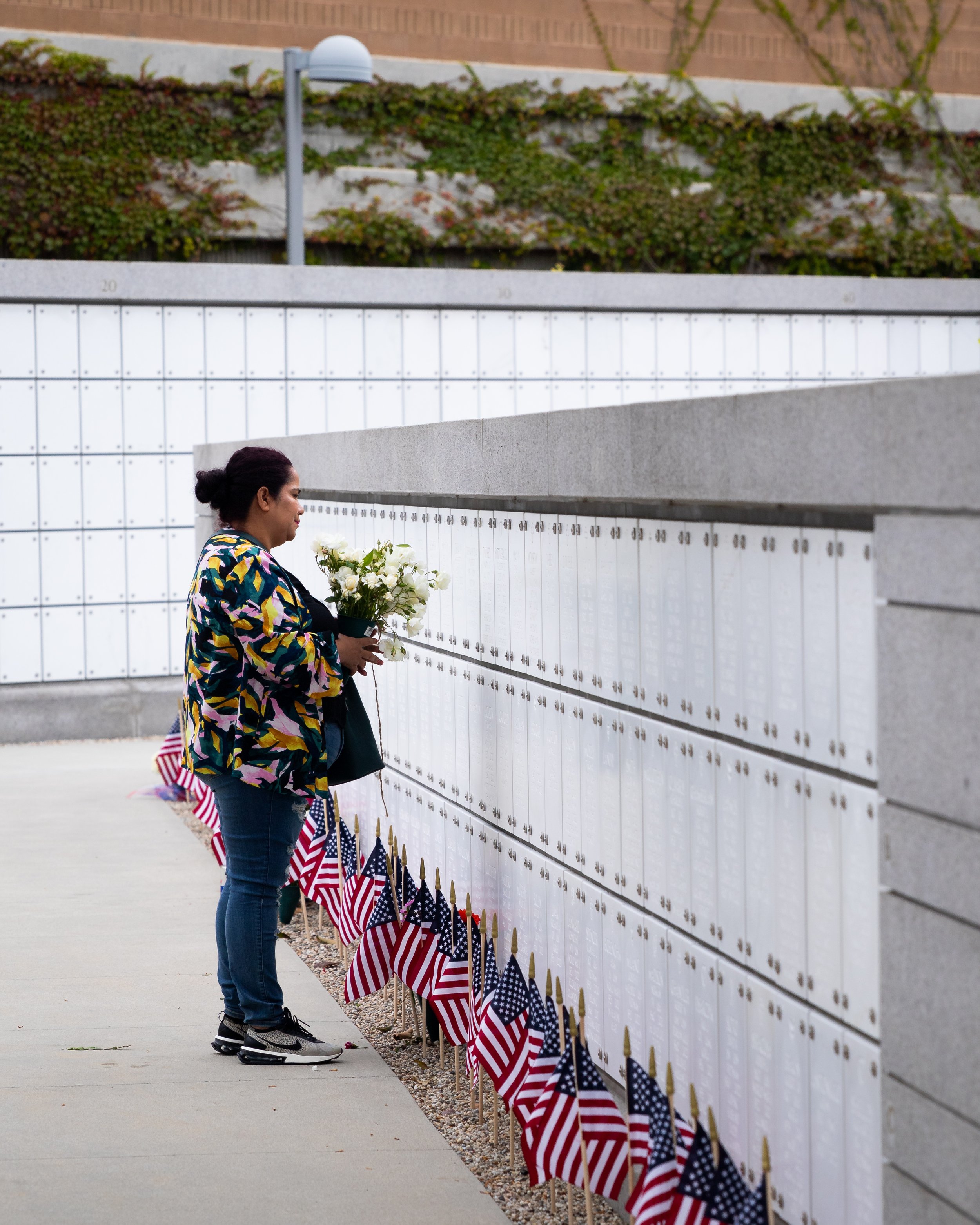  A woman holding flowers stands in front of graves before the Memorial Day Celebration at Los Angeles National Cemetery begins in Los Angeles, Calif., on Monday, May 29, 2023. (Caylo Seals | The Corsair) 