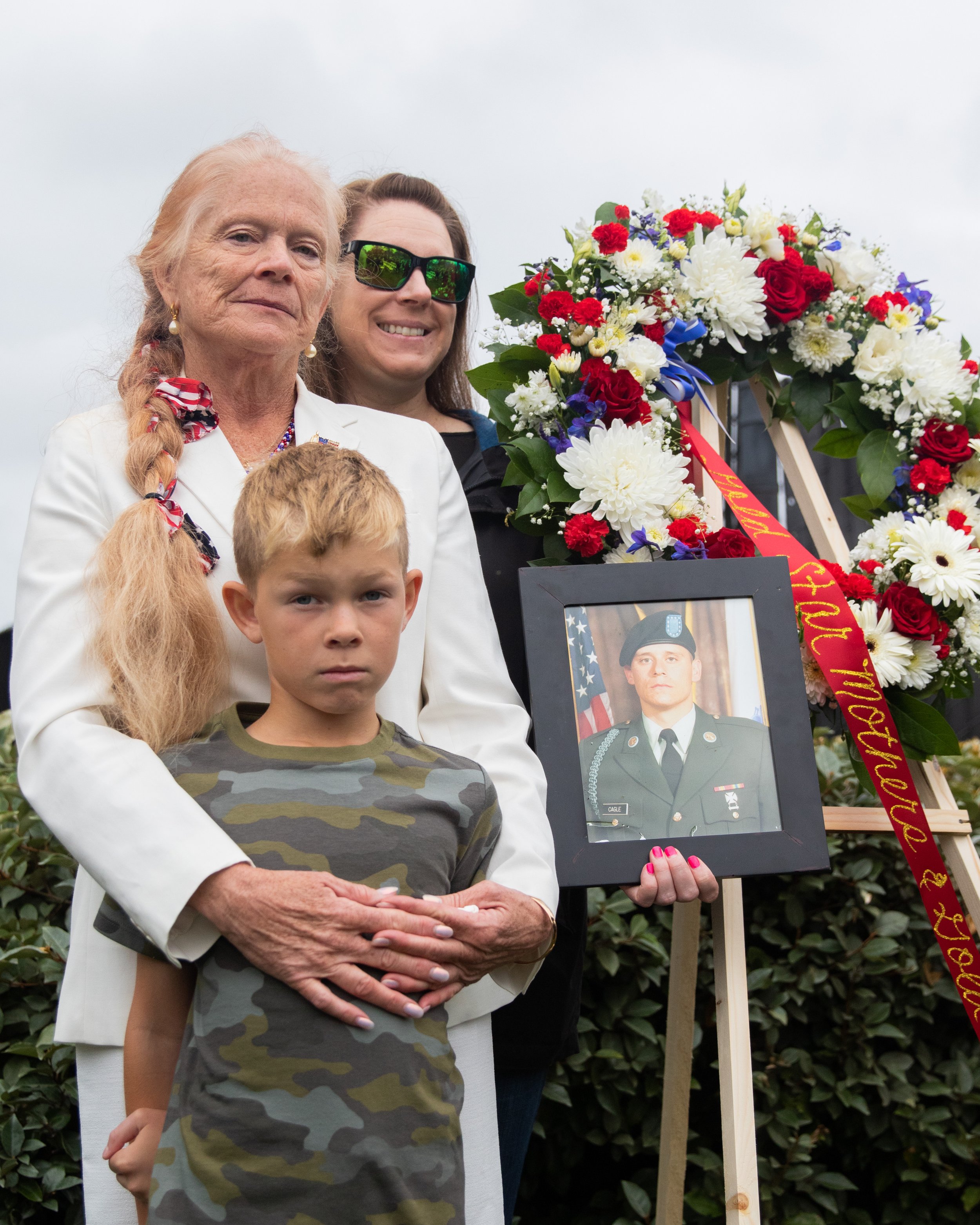  Gail Johnson (in white) with her daughter, grandson, and a picture of her son Daniel Cagle standing in front of the Gold Star Mothers and Wives Wreath during the Memorial Day Celebration at Los Angeles National Cemetery in Los Angeles, Calif., on Mo