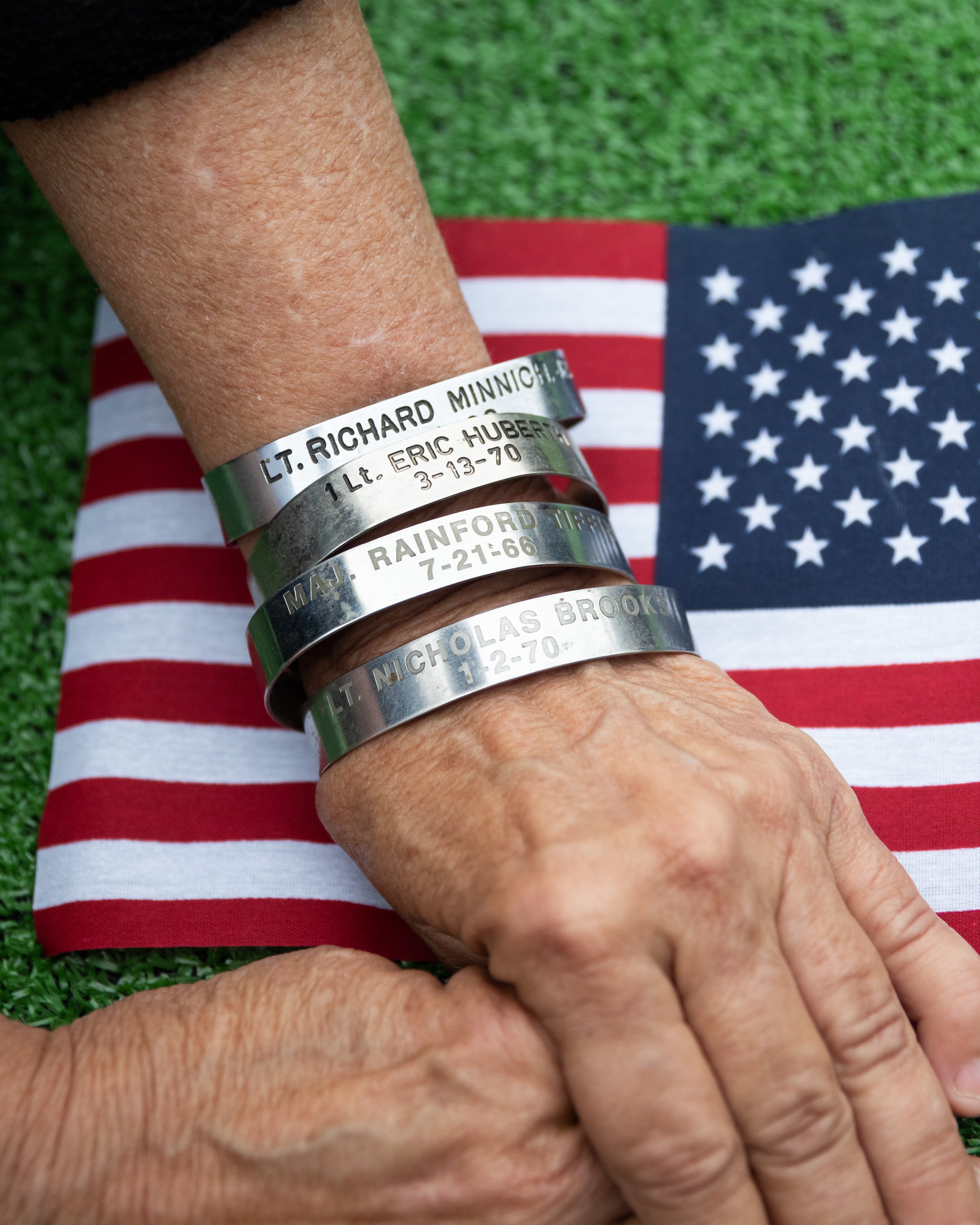  Robin Dominguez wearing POW/MIA bracelets rests her hands on the American Flag during the Memorial Day Celebration at Los Angeles National Cemetery in Los Angeles, Calif., on Monday, May 29, 2023. The bracelets have the names of those who are prison