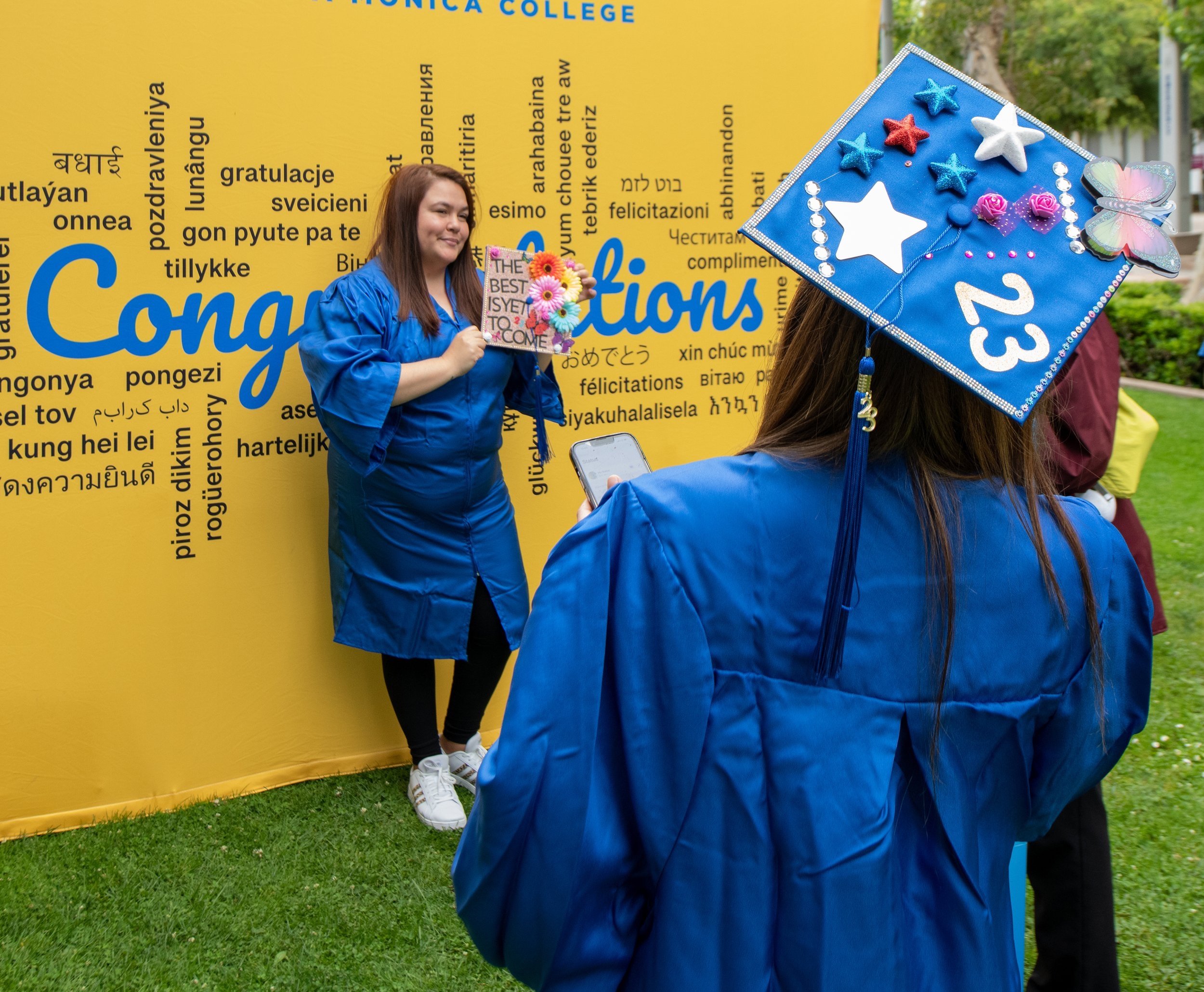  Students pose in front of the background set up for graduates at Grad Fest Thursday, June 1 at Santa Monica College Main Quad ( Kevin Tidmore | TheCorsair ) 