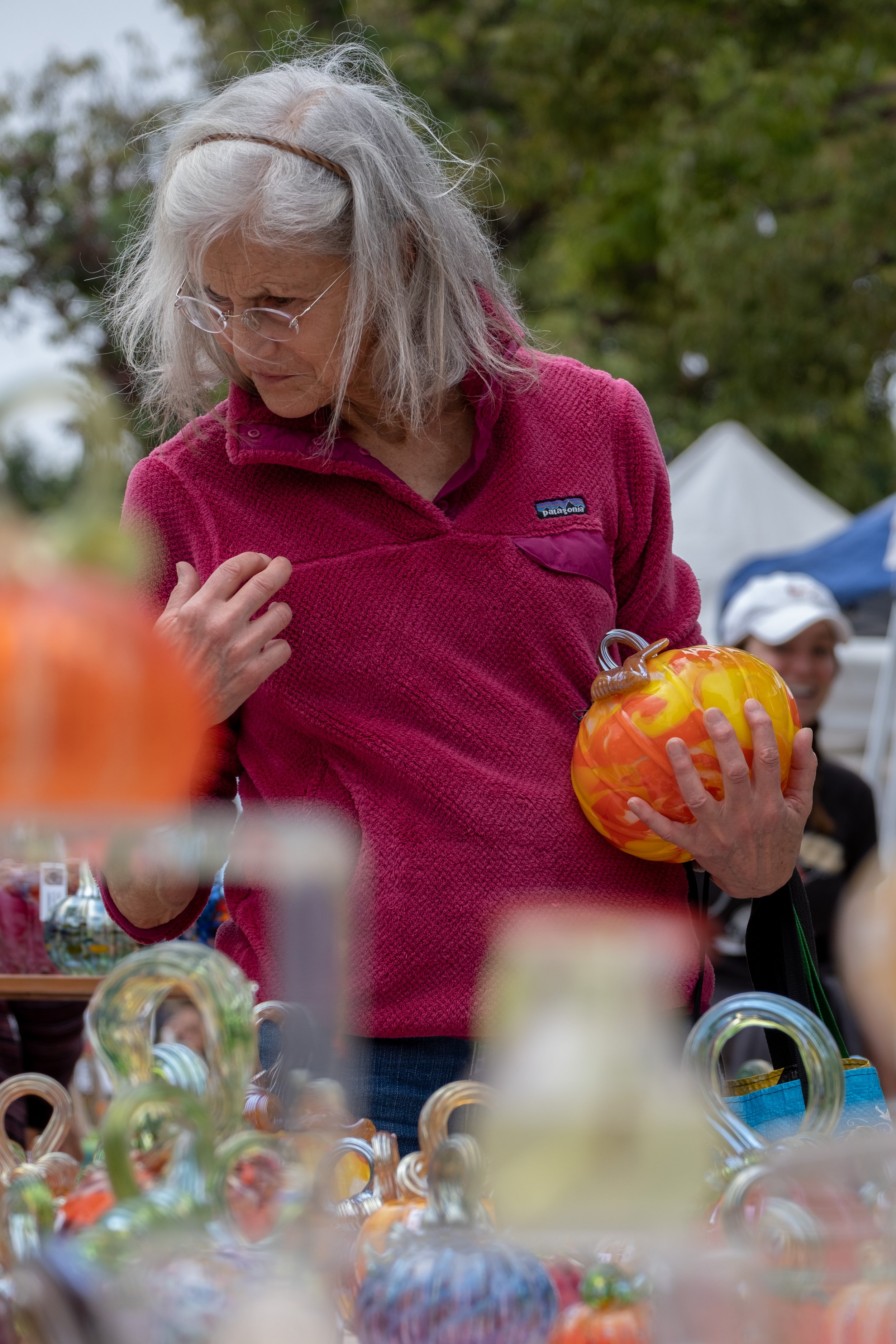  Robin, a patron at the Santa Monica College Glass Pumpkin Sale in Virginia Avenue Park in Santa Monica, Calif. on Saturday, Sept. 30th, 2023, cradles a glass pumpkin in her arm as she searches for a gift for a friend. (Akemi Rico | The Corsair) 