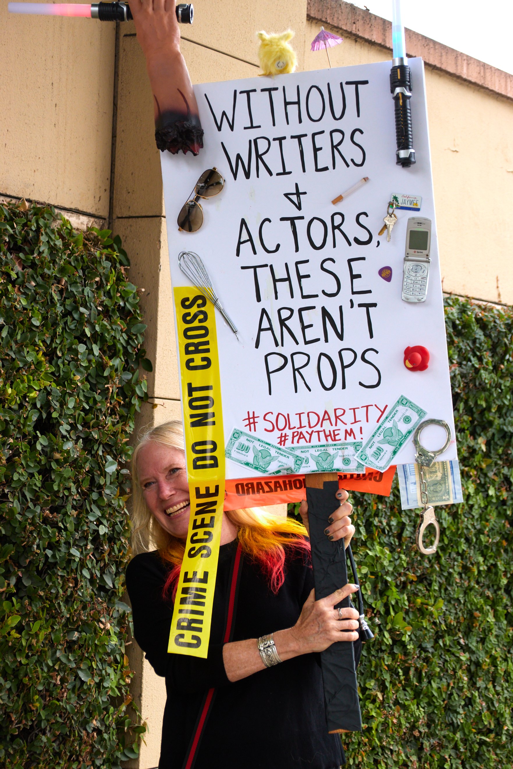  A marching picketer holds up a picket sign with various props and "WITHOUT WRITERS & ACTORS THESE AREN'T PROPS" written on it during the SAG-AFTRA strike in front of Warner Bros. Studio, Burbank, Calif., on Sept 29, 2023. (Danniel Sumarkho | The Cor