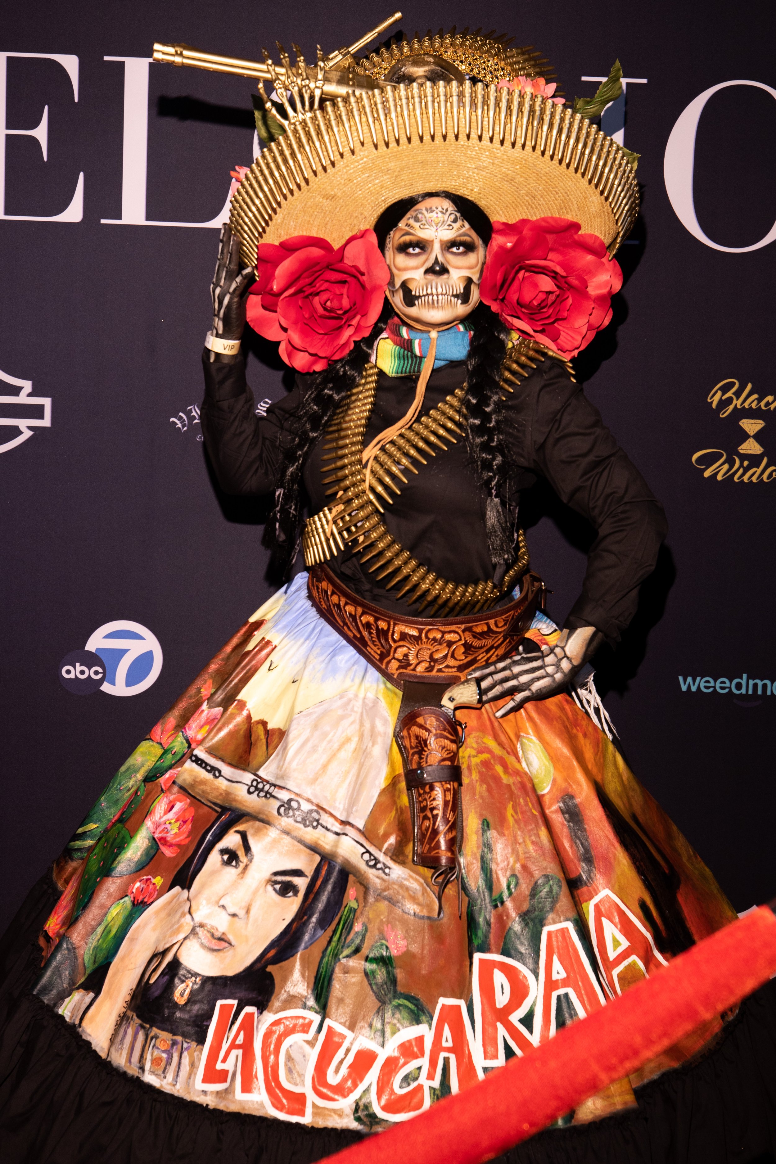  A woman wearing a Catrina costume poses in front of the step and repeat banner at the entrance to El Velorio's 13th Day of the Dead Music & Arts Festival at La Plaza de la Raza, Los Angeles, Calif. on Saturday Oct. 14, 2023. (Akemi Rico | The Corsai