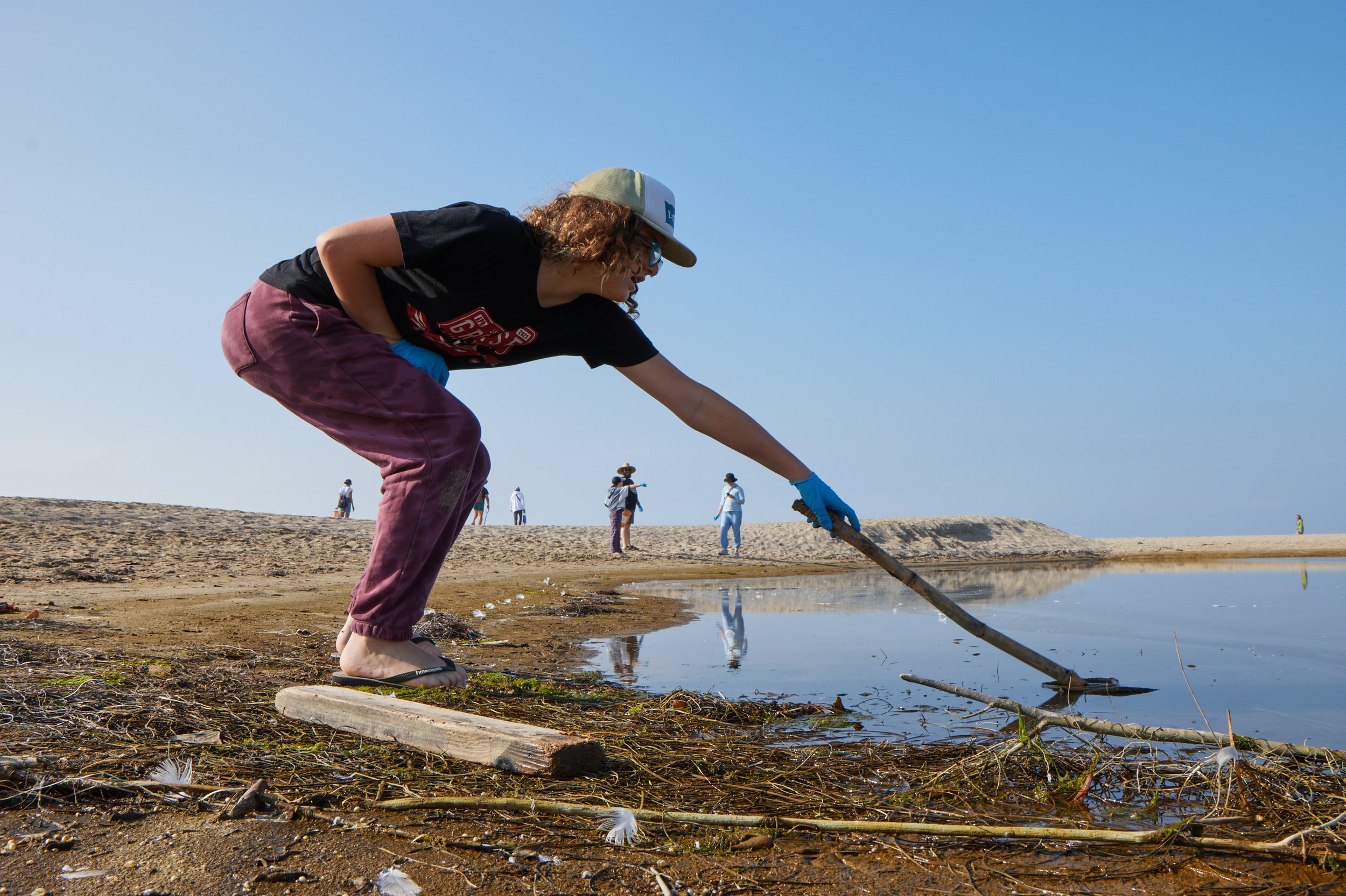  Volunteer Xavier attempts to pick up a piece of trash with a stick in a lagoon during a coastal beach cleanup organized by Santa Monica College Sustainability Center at The Inkwell, Santa Monica, Calif., on Sept. 23, 2023. The heavily polluted lagoo