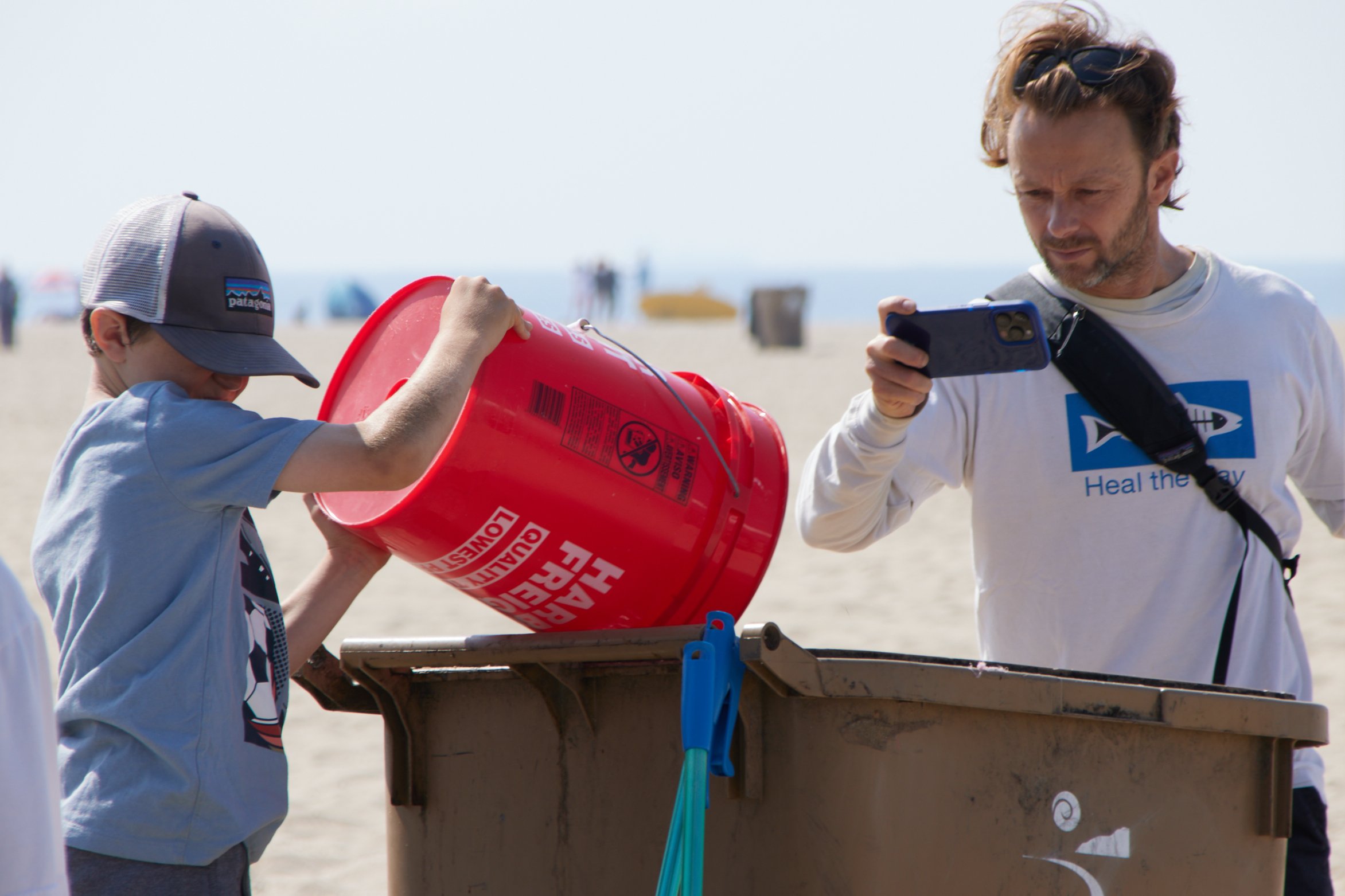  Marine biologist and professor at Santa Monica College (SMC) Benjamin Kay takes a video of his son Kody dumping a bucket full of collected trash into garbage bin during a coastal cleanup organized by SMC Sustainability Center at The Inkwell, Santa M