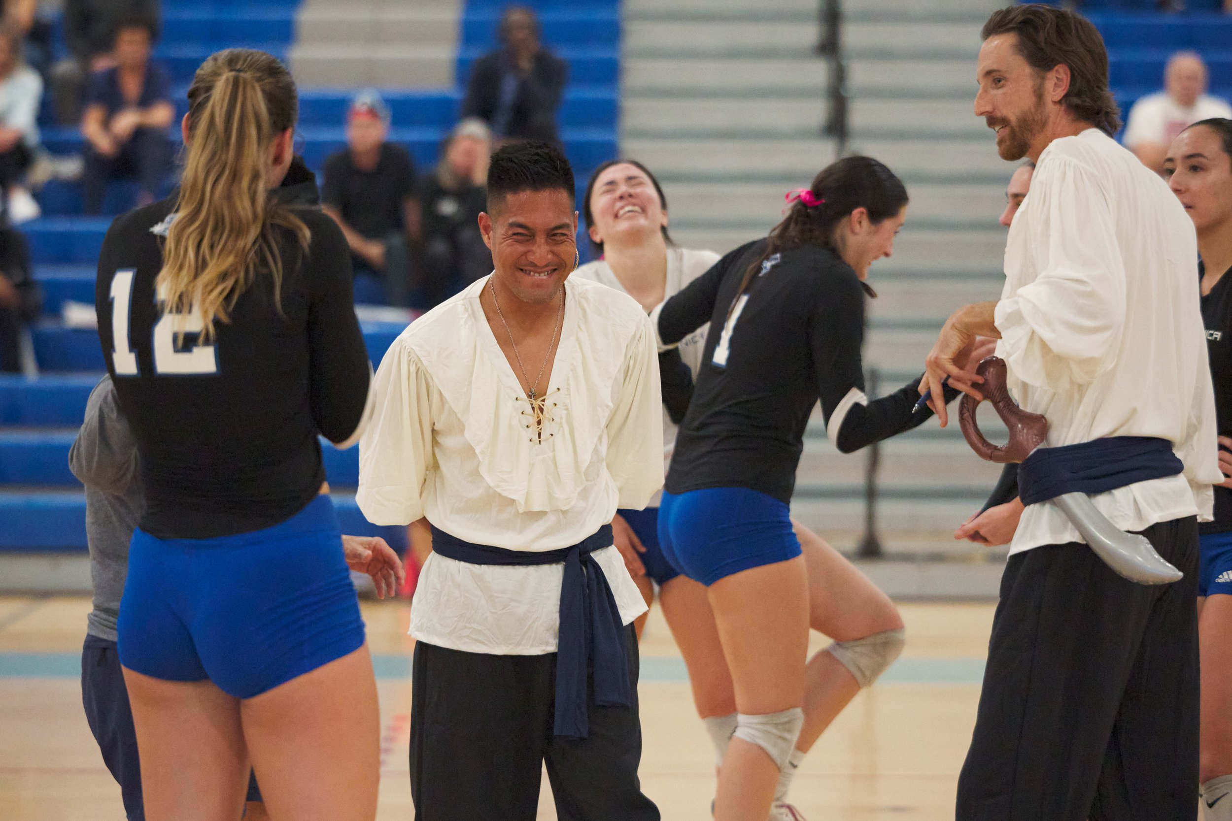  Santa Monica College Corsairs Women's Volleyball Head Coach Christian Cammayo (center left), next to assistant coach Chris Chown (right), fails to contain his laughter after Mia Paulson (left) got smacked in the face with the ball during the match a