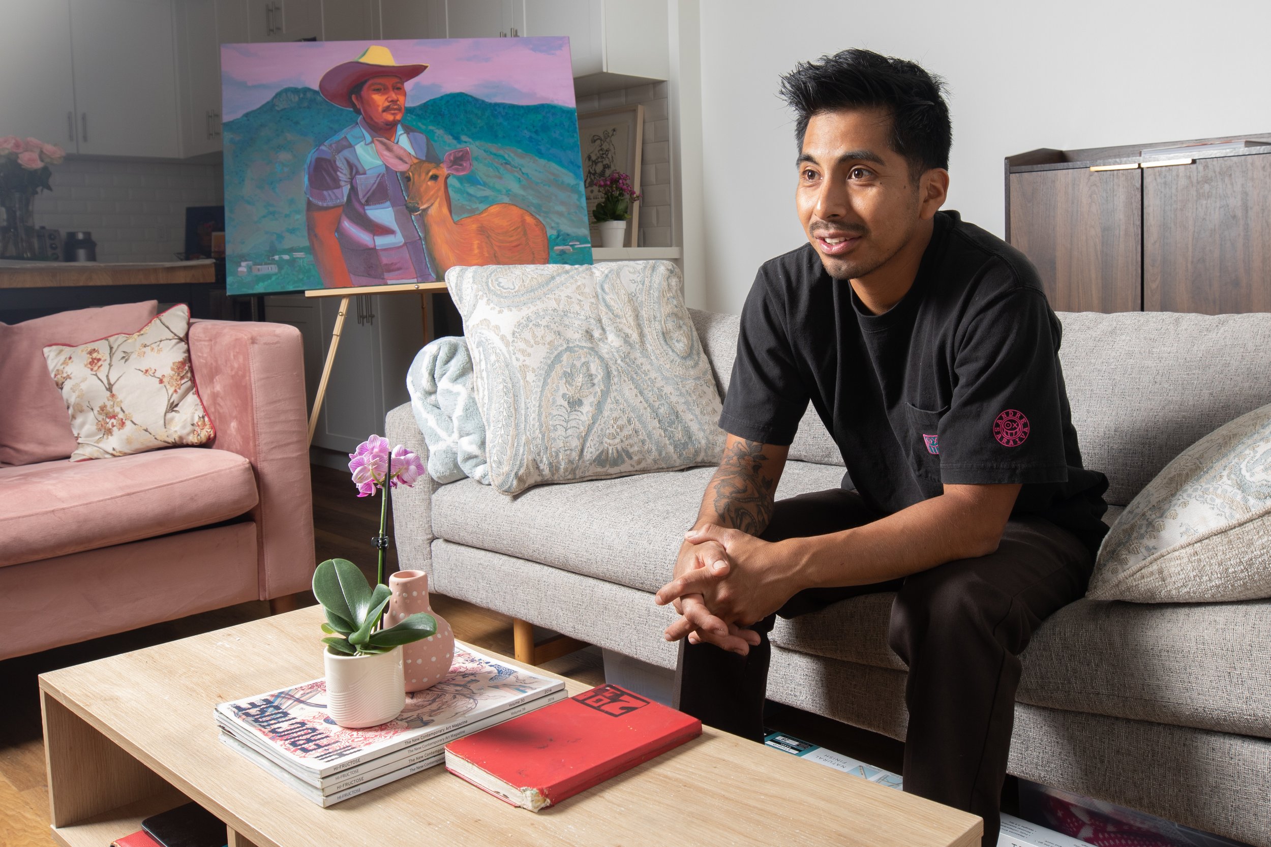  Oscar Lopez, Los Angeles artist and Santa Monica College alumni, at his home in Los Angeles, Calif. on Friday, Nov. 3, 2023. Behind him, a painting depicting his father is propped up on an easel. (Akemi Rico | The Corsair) 