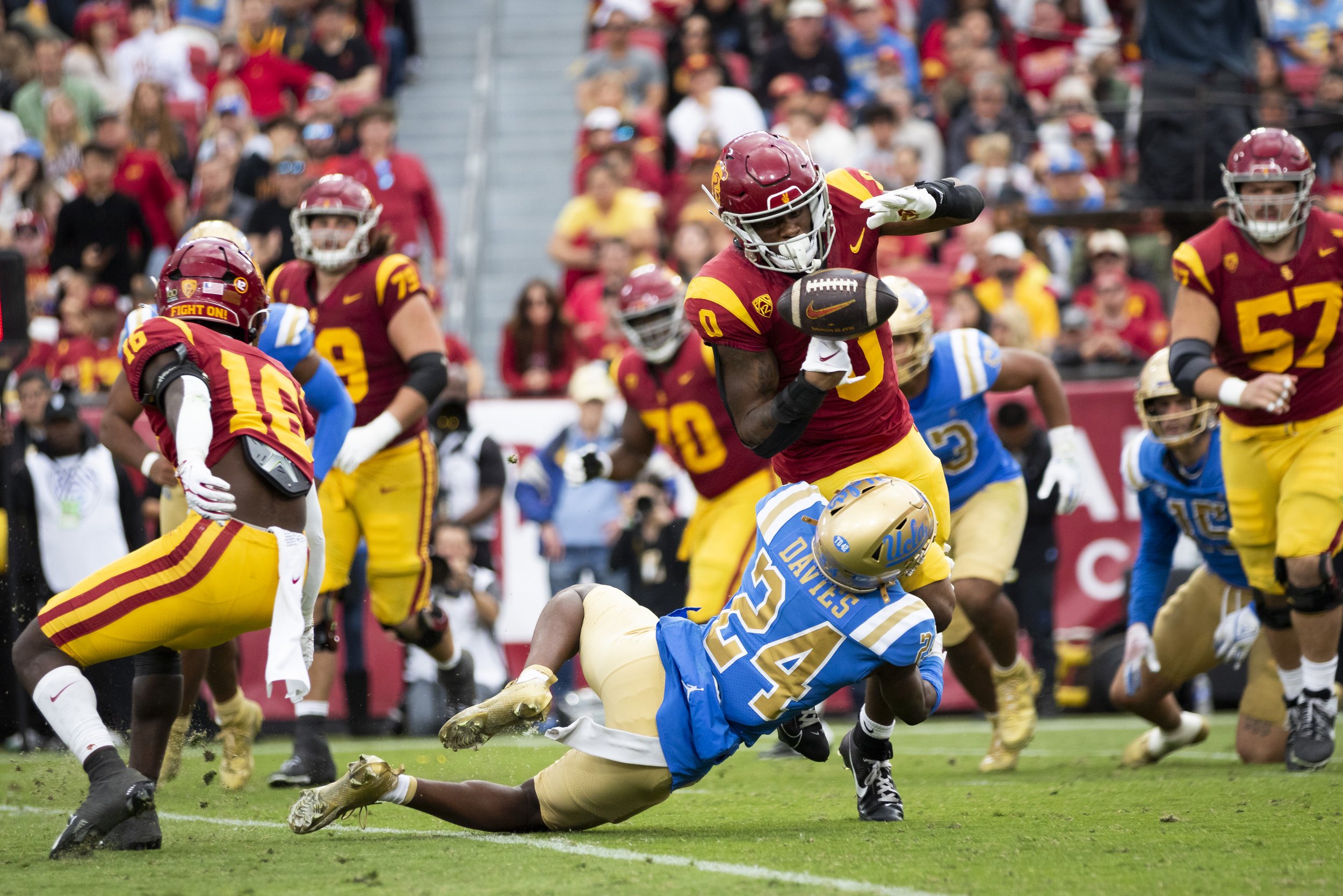  University of Southern California (USC) Trojan running back MarShawn Lloyd (center right) fumbling the ball while getting tackled by University of California, Los Angeles (UCLA) Bruin defensive back Jaylin Davies (center left) during the third quart