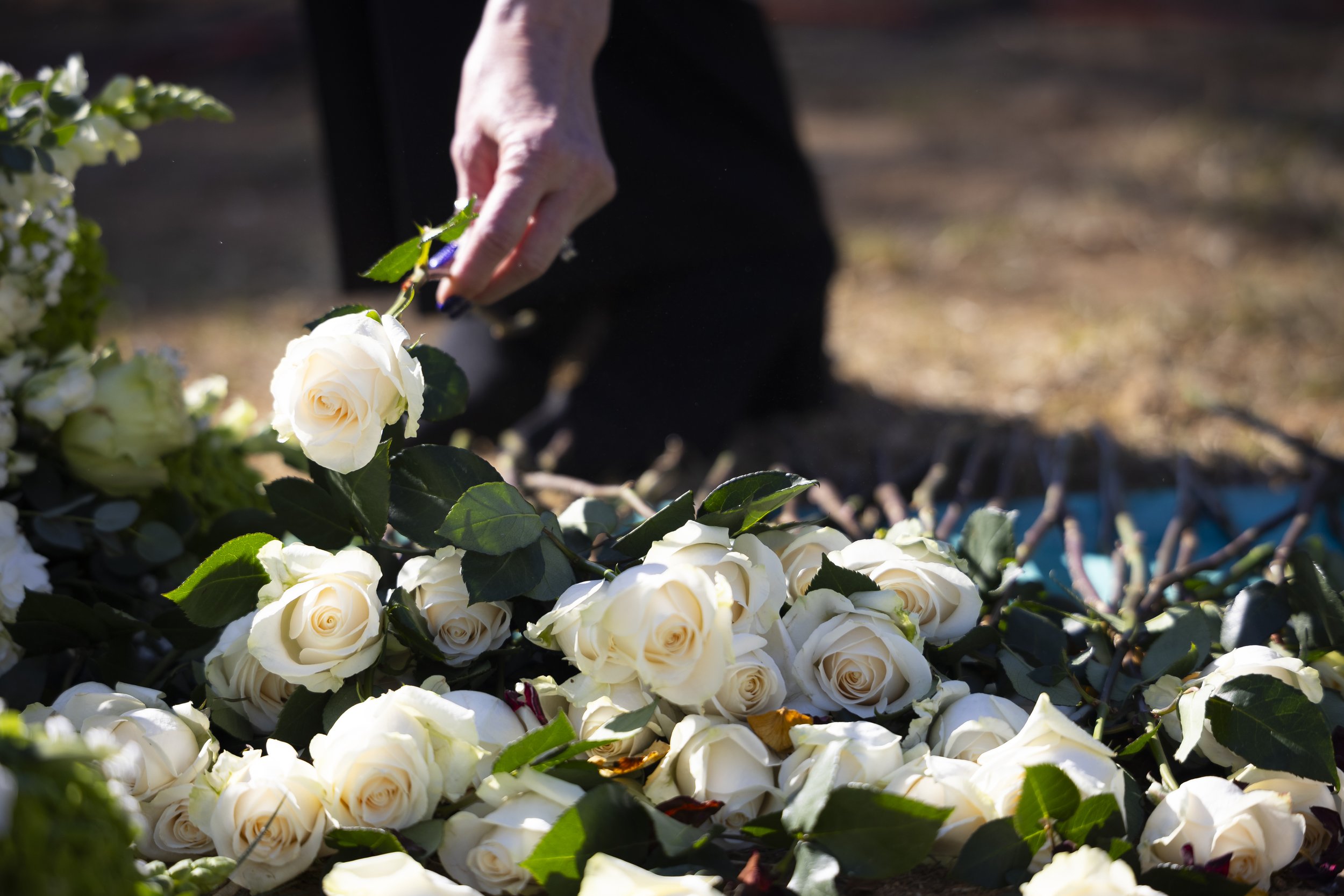  A women places a white rose on the grave marking the 1,937 individuals who died in 2020 and either did not have next of kin, or were not claimed by their next of kin during LA County Ceremony of the Unclaimed Dead at the LA County Cemetery, in Los A