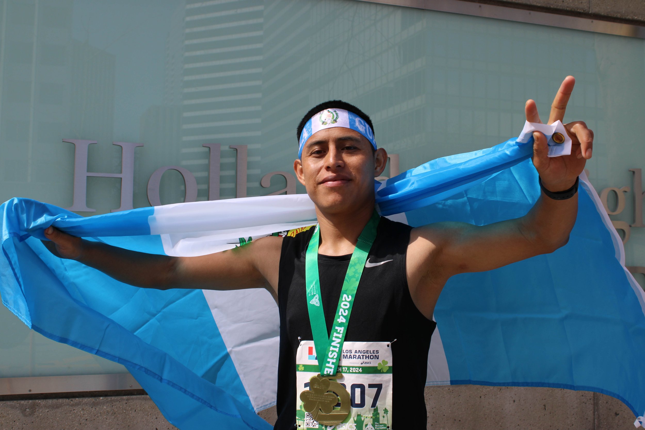  Runner Hernando Perez gives victory cry in front of his Guatamalan flag after completeing Los Angeles 2024 Marathon 