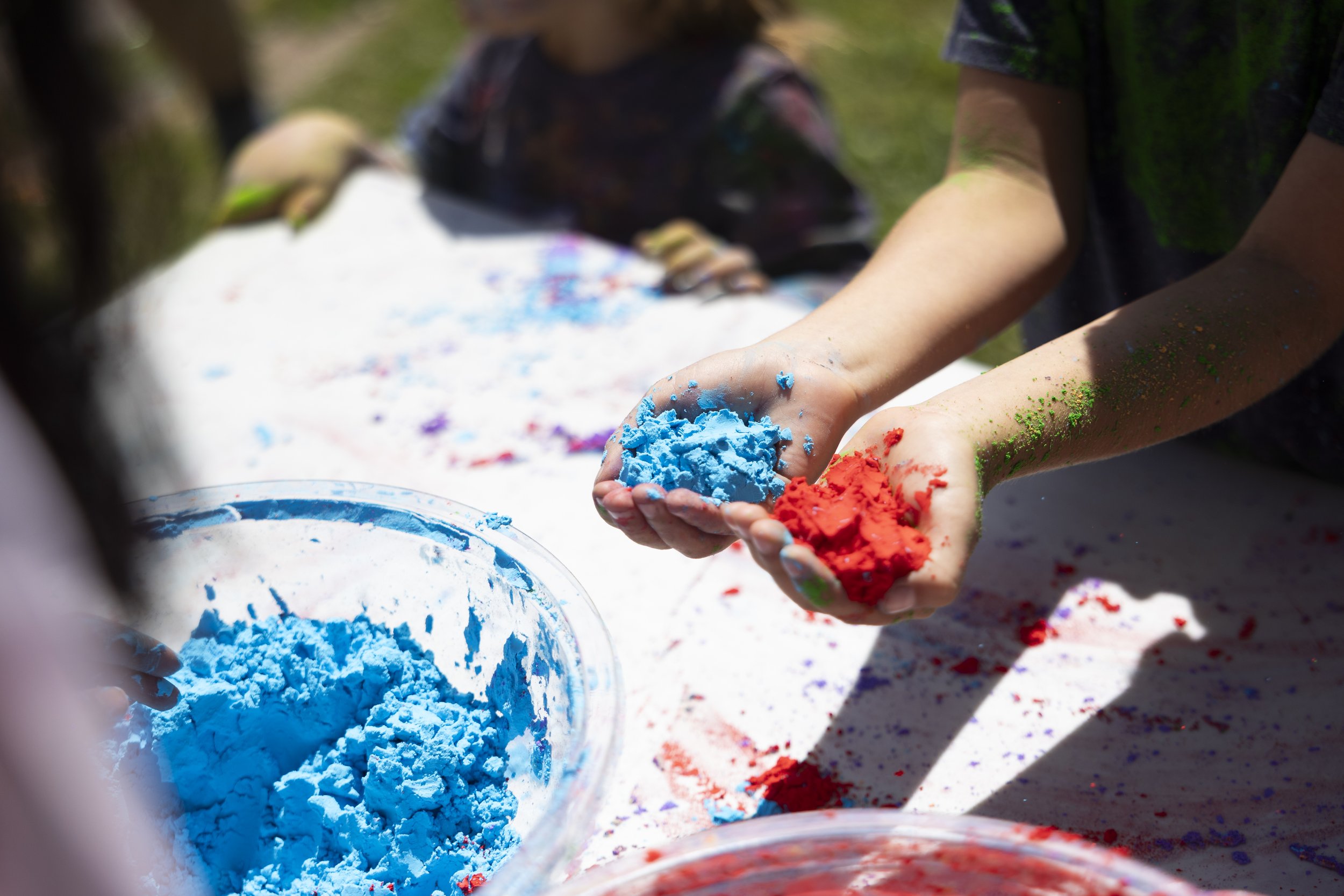  A child picks up more blue and red Holi powder at the second annual Venice Holi Celebration at Penmar Park in Los Angeles, Calif., on Sunday, April 7, 2024. The different colored powders symbolize different things, for example, red symbolizes marria